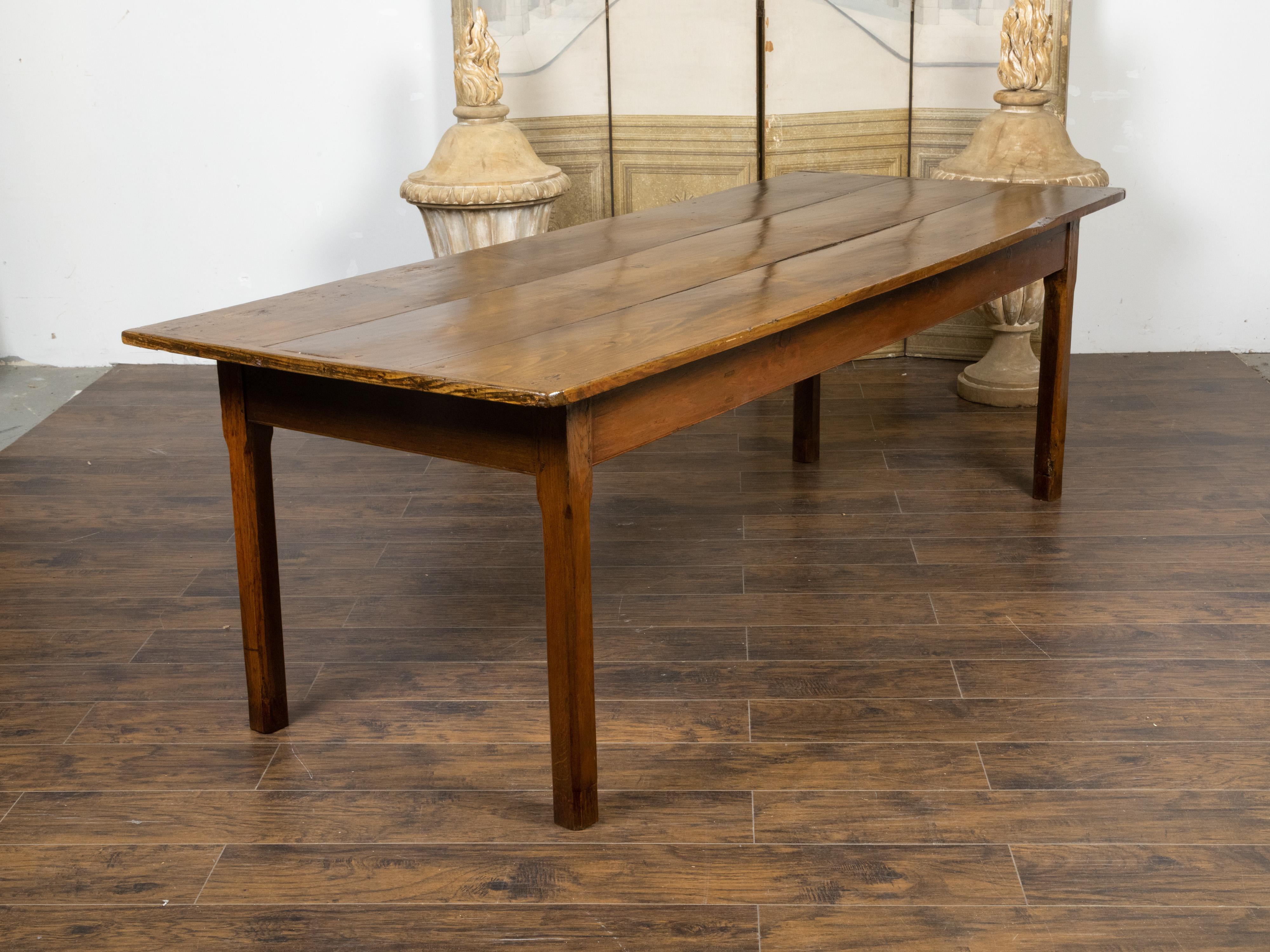 A large rustic Country French pine farm dining table from the 19th century, with straight legs, dark patina and distressed appearance. Created in France during the 19th century, this farm pine table features a rectangular planked top with rounded