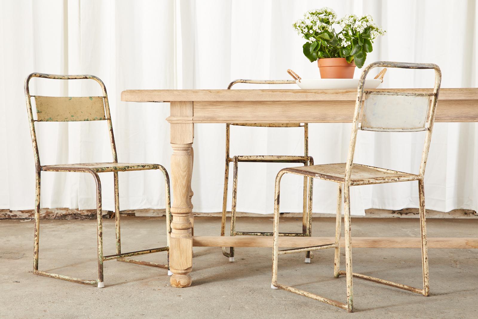 Contemporary bleached oak farmhouse dining table made in the country French style. The table features a 1.5 inch thick plank top supported by a trestle style base. The oak has a beautiful aged patina on the natural finish. Ample legroom measuring 24