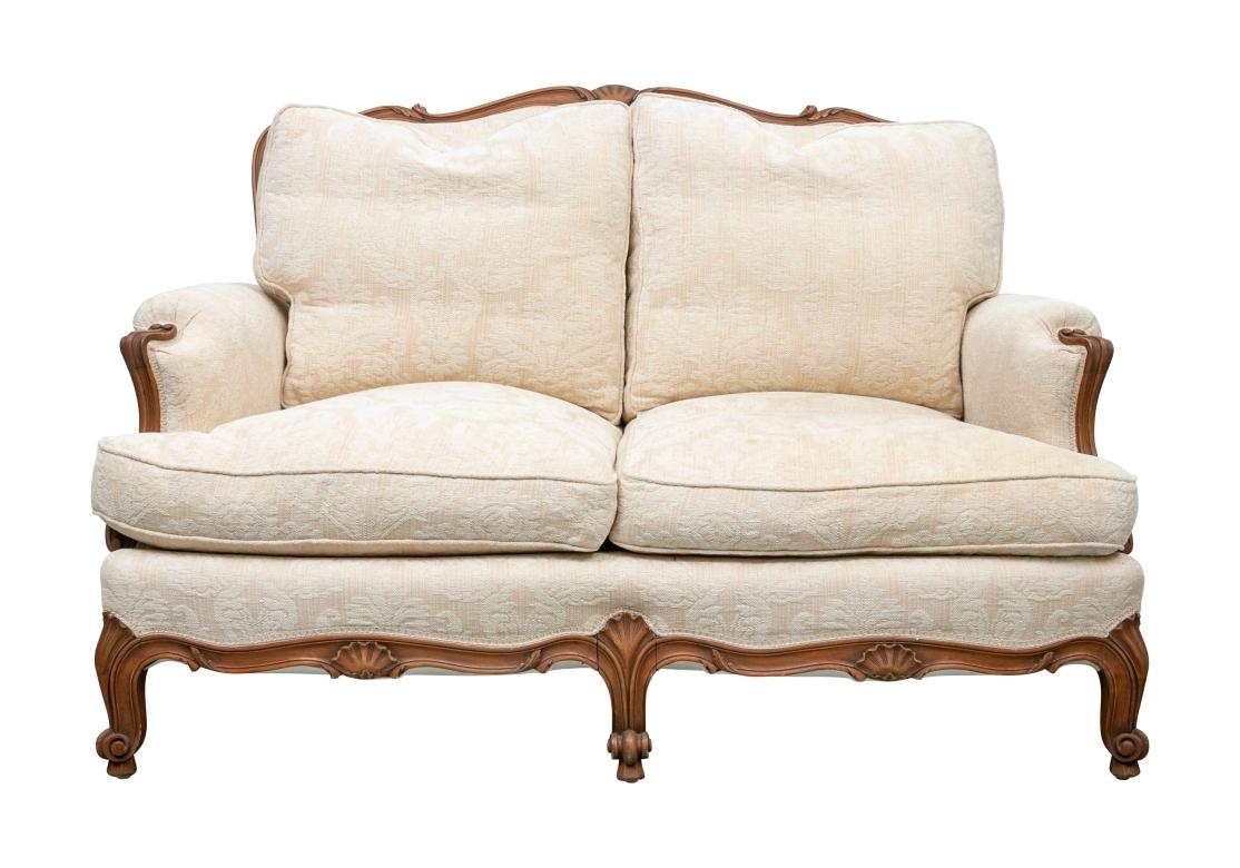A sumptuous and well made  two seat sofa with carved serpentine crest rail and carved arms. The scrolled cabriole legs on a shaped skirt rail. Upholstered in a pale yellow textured damask type print with comfortable cushions. 

W. 52