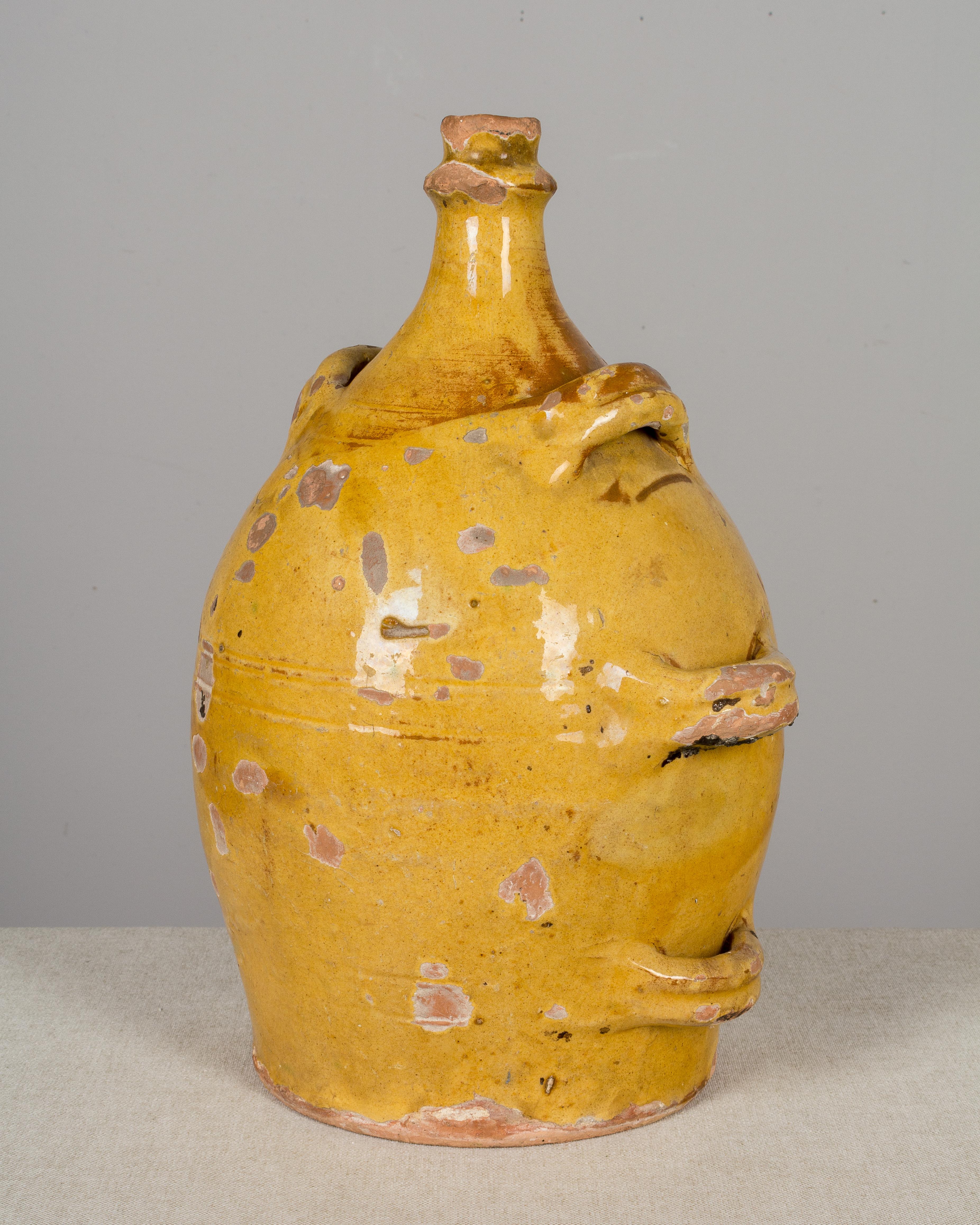 A 19th century earthenware pottery jug from the Southwest of France with traditional ochre yellow glaze. This unusual terracotta pot has six handles up the sides and was used to store vinegar. Beautiful patina and warm yellow color. Minor losses to