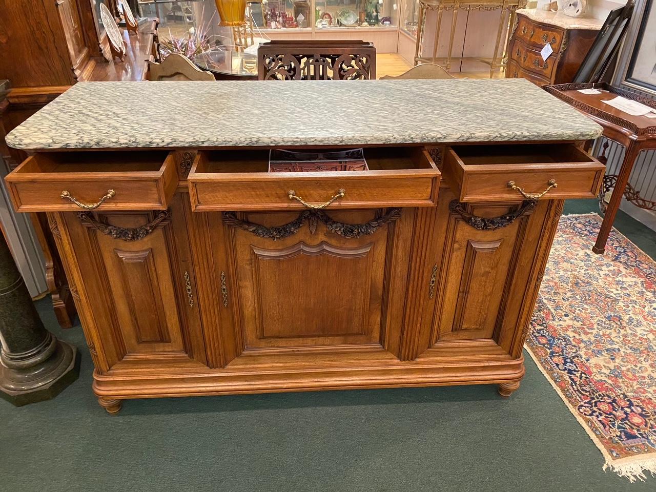 Beautiful French carved walnut console that can be used under a TV in a bedroom or family room or as a traditional sideboard in a dining room. This statement piece can work anywhere you want to make a statement. The solid marble is original and is