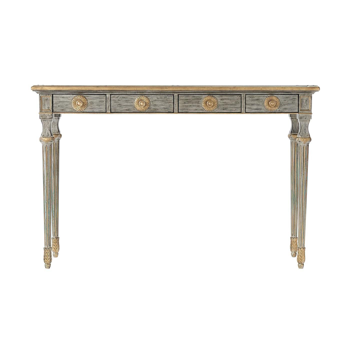 A country house grey painted grained mahogany and gilt highlighted console table, the rectangular top above four frieze drawers with gilt rosettes and brass handles, on turned tapering fluted legs with carved capitals and leaf cast brass feet.