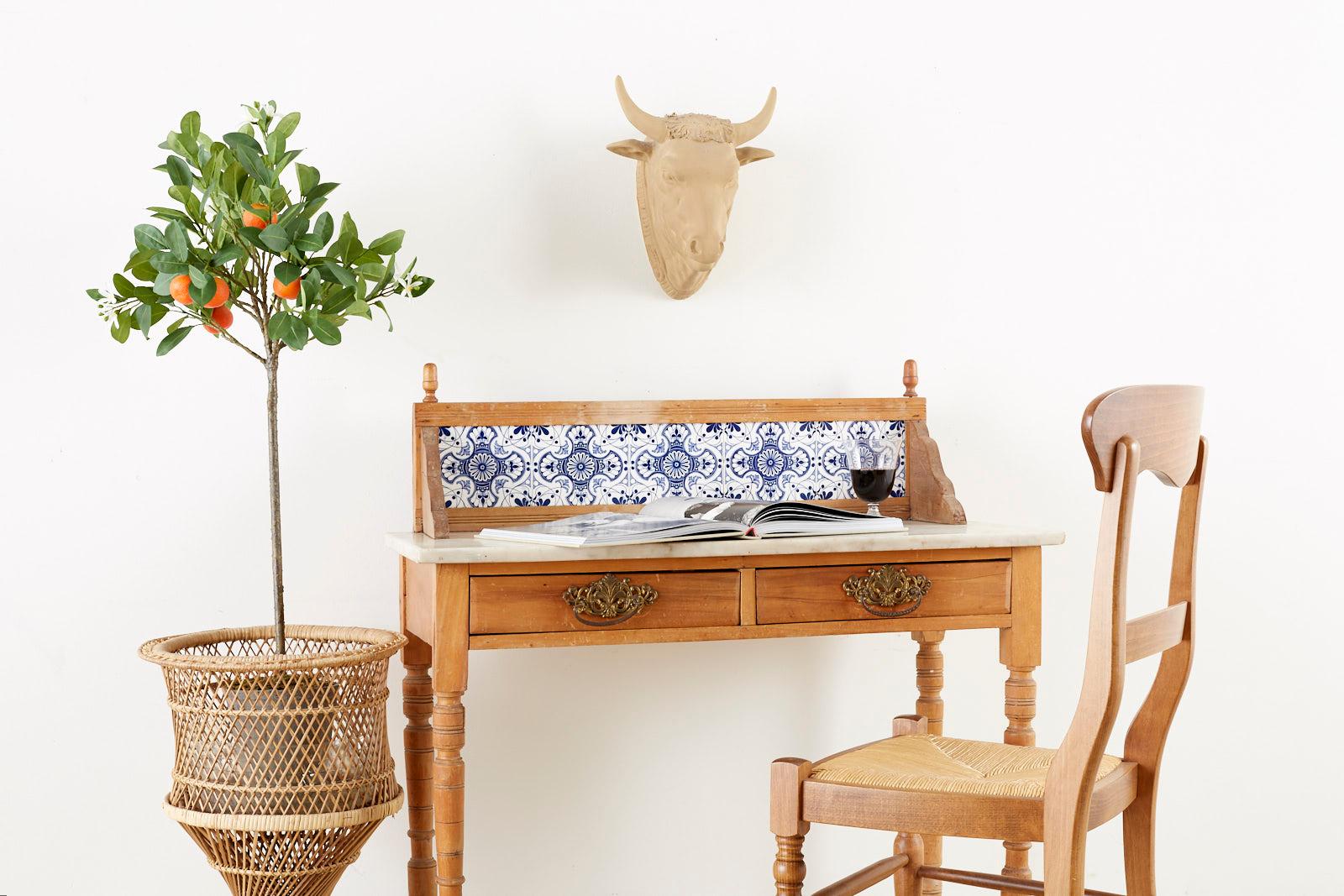 Country pine writing desk or work table featuring a marble top. Fronted by two storage drawers. Mediterranean blue and white tiles decorate the backsplash with round finials on the corners. Each drawer has brass pulls and the table is supported by