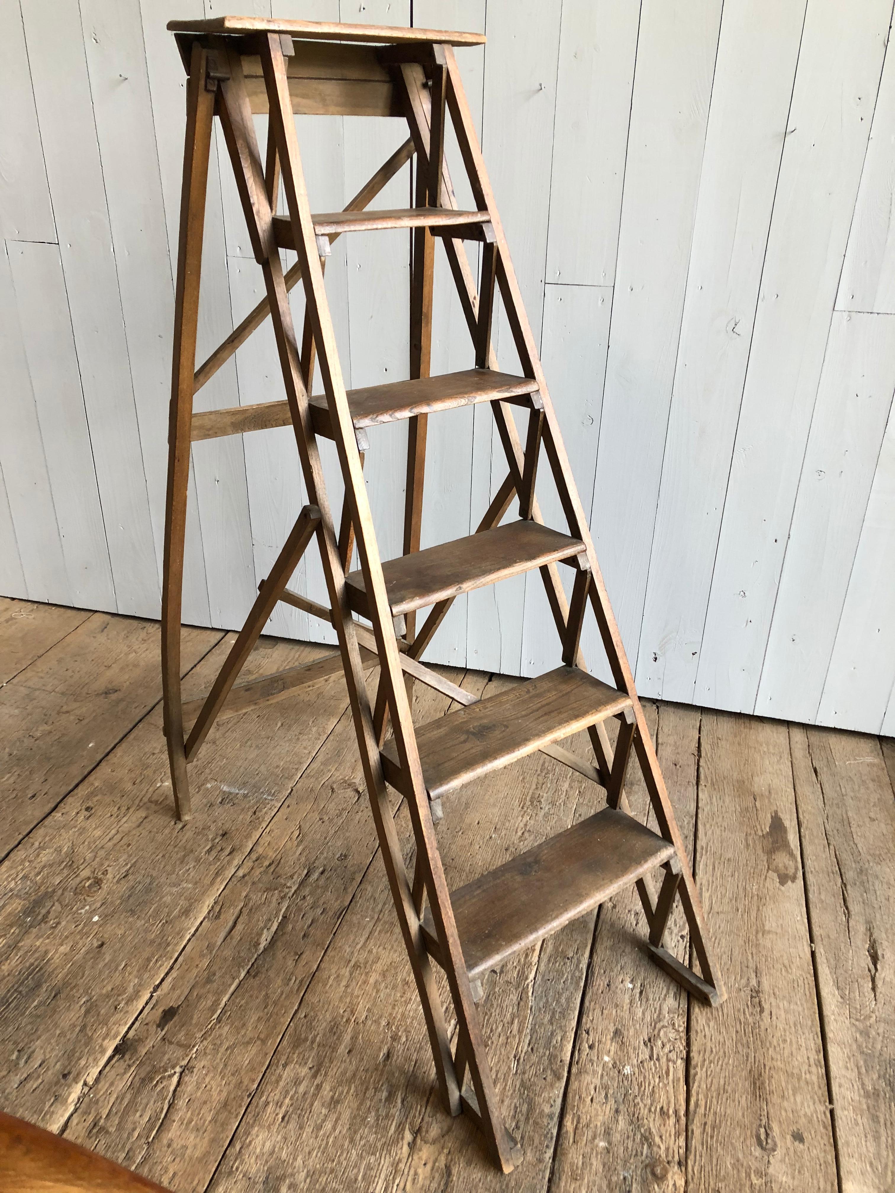 A charming 19th century folding ladder, likely from a general store or library, with 6 steps and a warped rear leg for character. Very sturdy.