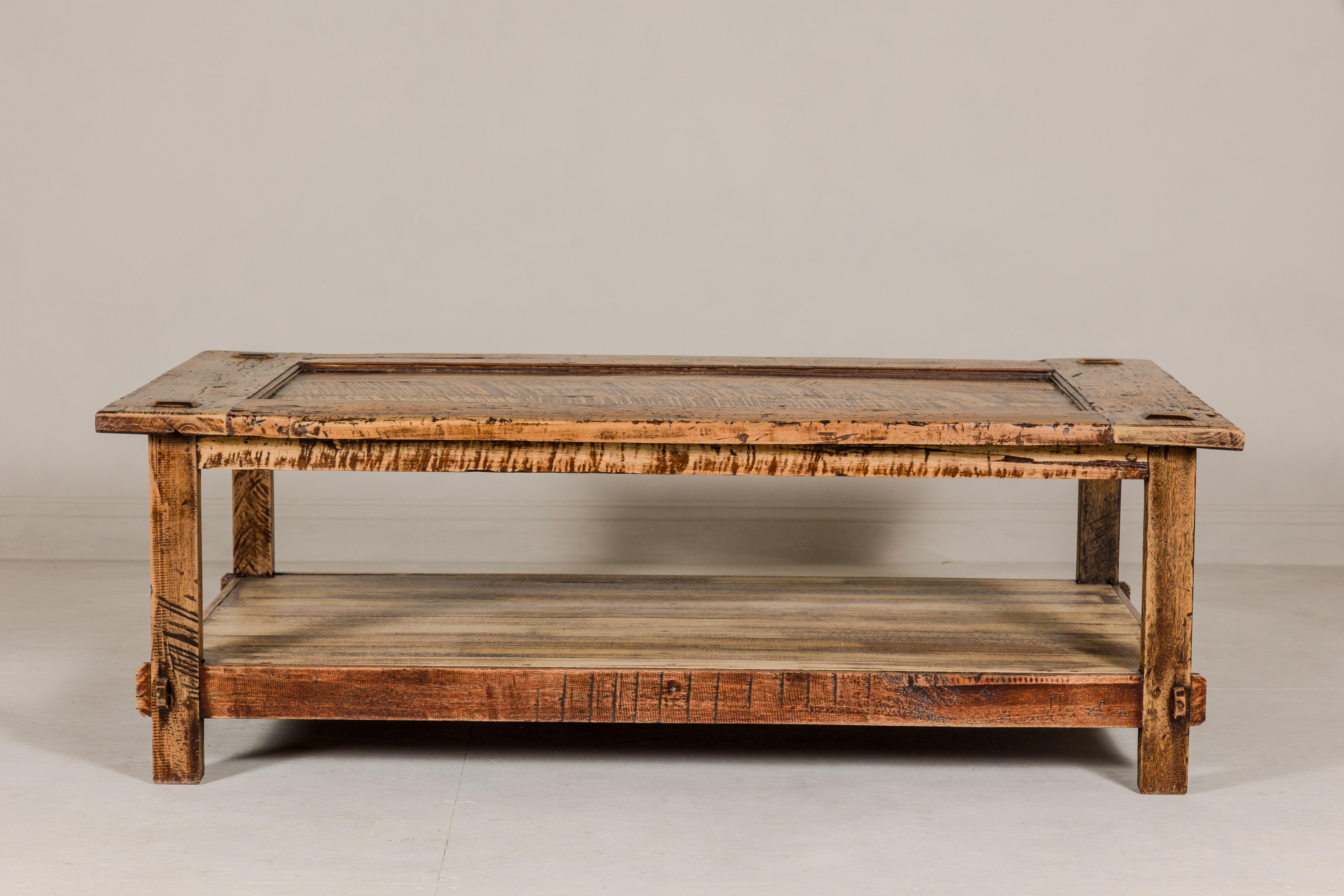 A vintage two-tier coffee table from the mid 20th century with inset top and distressed finish. Immerse yourself in the charm of bygone eras with this vintage two-tier coffee table, meticulously crafted in the mid-20th century. Boasting a timeless