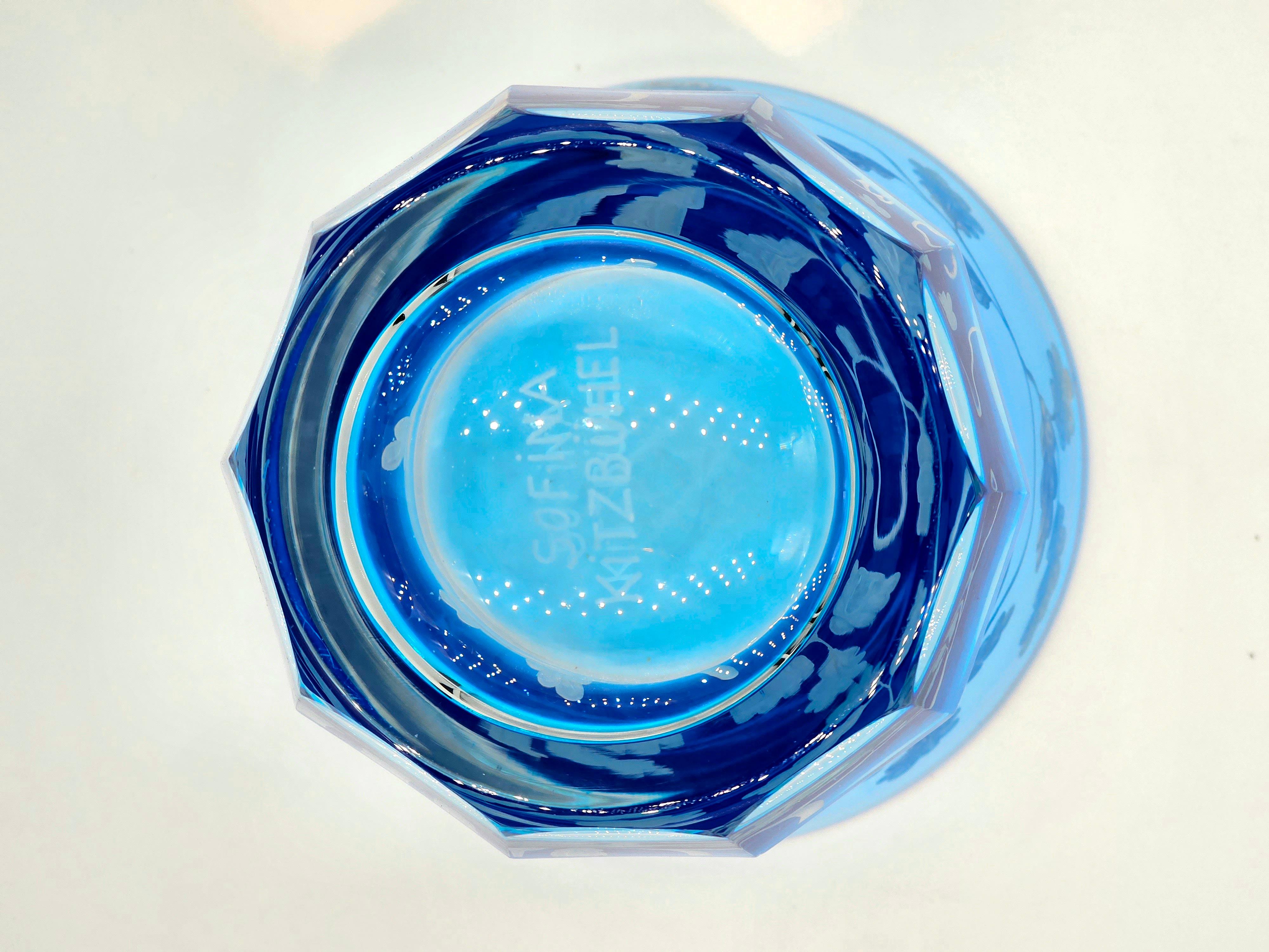 Vase aus mundgeblasenem Kristall in leuchtend blauem Glas mit einem Dekor aus Vögeln und Eichenblättern rundherum. Das Dekor wird von Künstlern freihändig graviert und der Boden des Glases wird von Hand geschnitzt. Das hier gezeigte blaue Glas kann