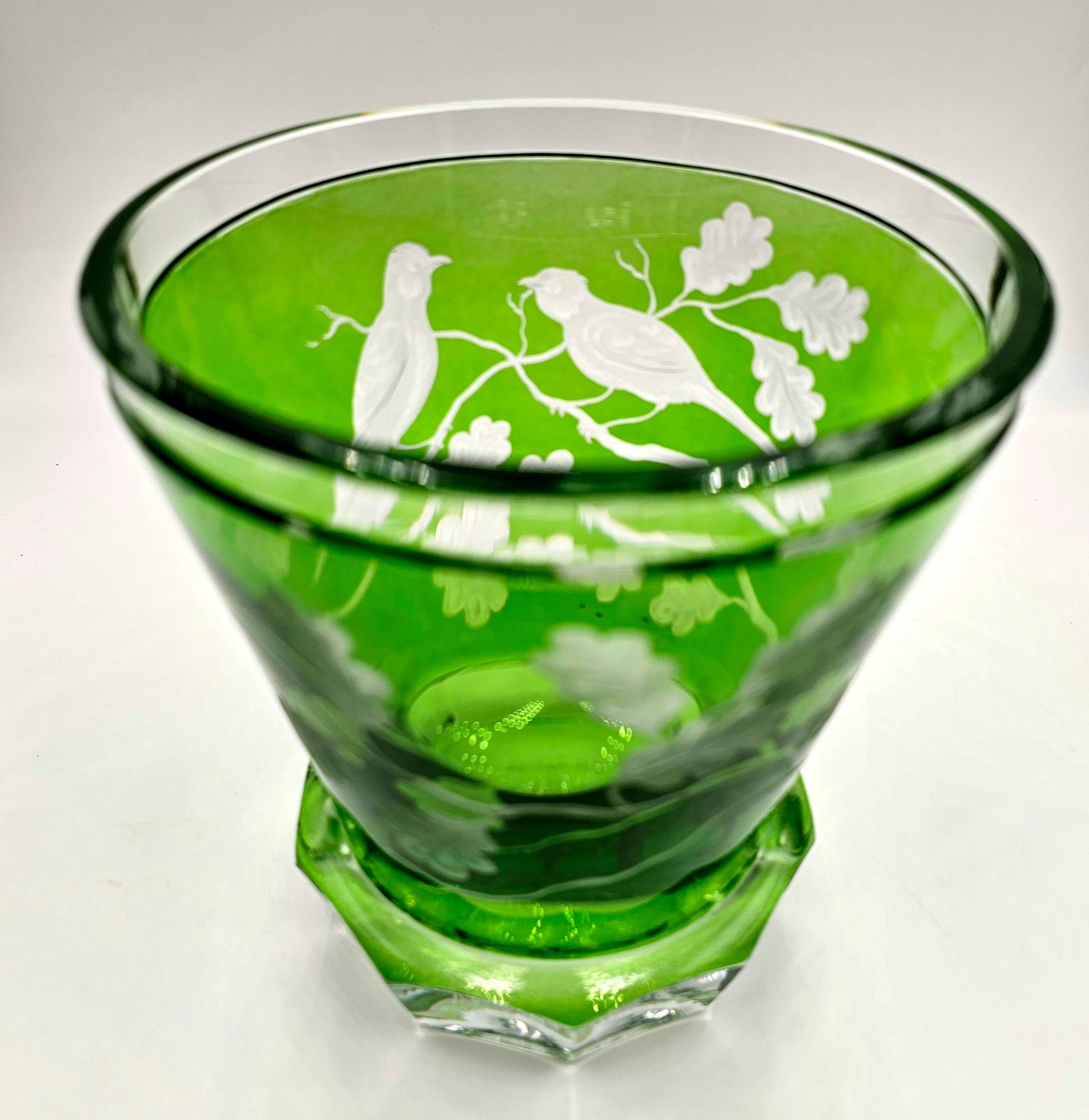 Vase aus mundgeblasenem Kristall in grünem Glas mit einem Dekor aus Vögeln und Eichenblättern rundherum. Das Dekor wird von Künstlern freihändig graviert und der Boden des Glases wird von Hand geschnitzt. Das hier gezeigte Glas in grüner Farbe kann