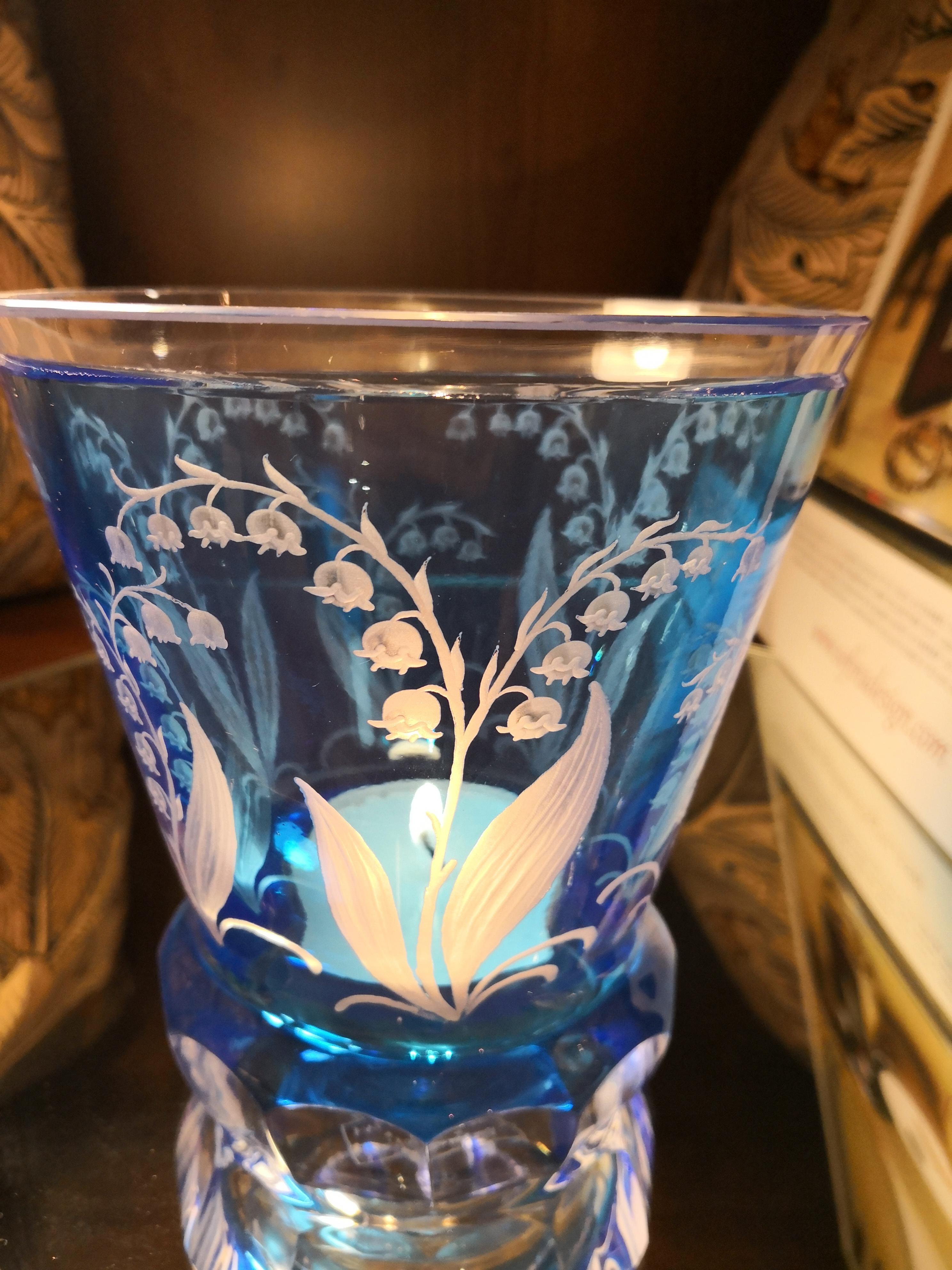 Vase/lanterne en cristal soufflé à la main en verre bleu clair avec décor de muguet tout autour. Les fleurs et les feuilles sont gravées à la main par des artistes verriers en Bavière/Allemagne. Le verre est de couleur bleu clair et peut être