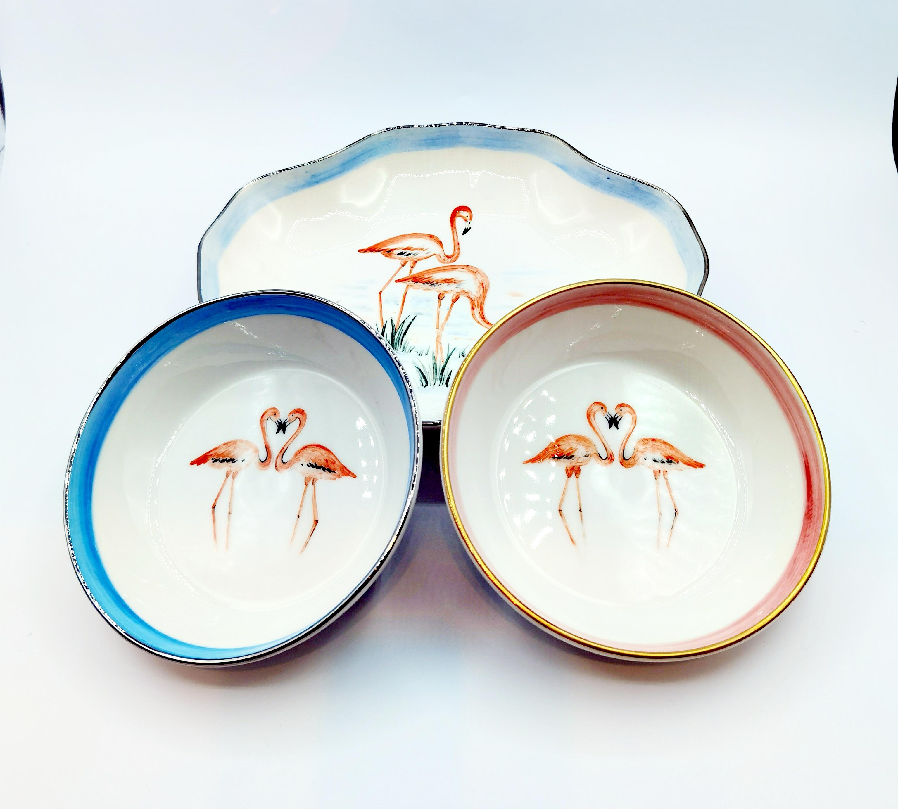 Handmade and free-hands painted porcelain dish in a classic oval shape.
Handsfree painted with a pair of flamingos in the middle of the dish with a blue color rim and platin rimmed. Backside stamped Sofina. 
Sofina Boutique Kitzbühel porcelain is