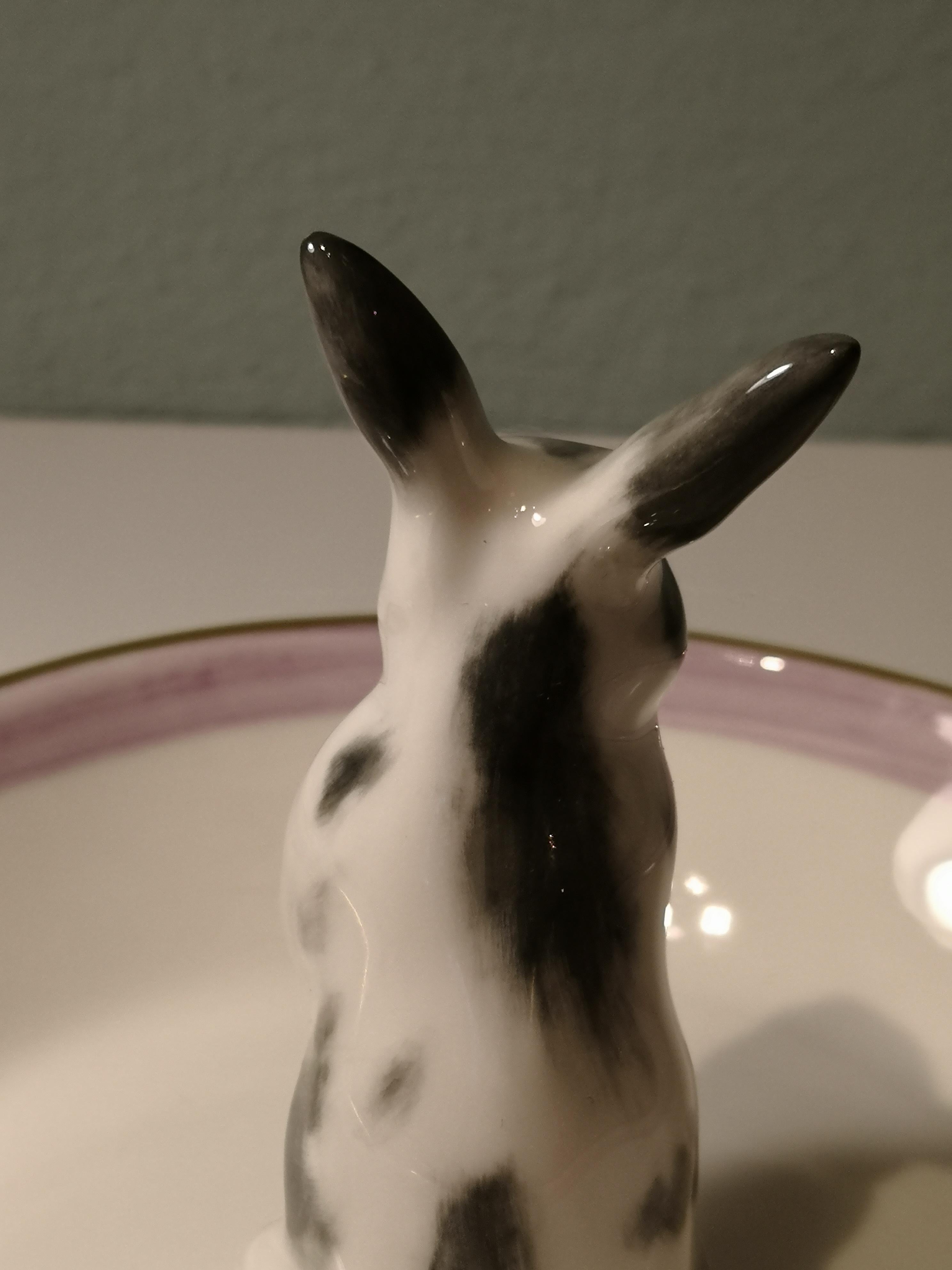 Completely handmade porcelain bowl with a hands-free naturalistic painted bunny figure with grey spots in country style. The bunny is sitting in the middle of the bowl for decorating nuts or sweets around. Rimmed with a pink and 24-carat gold line.