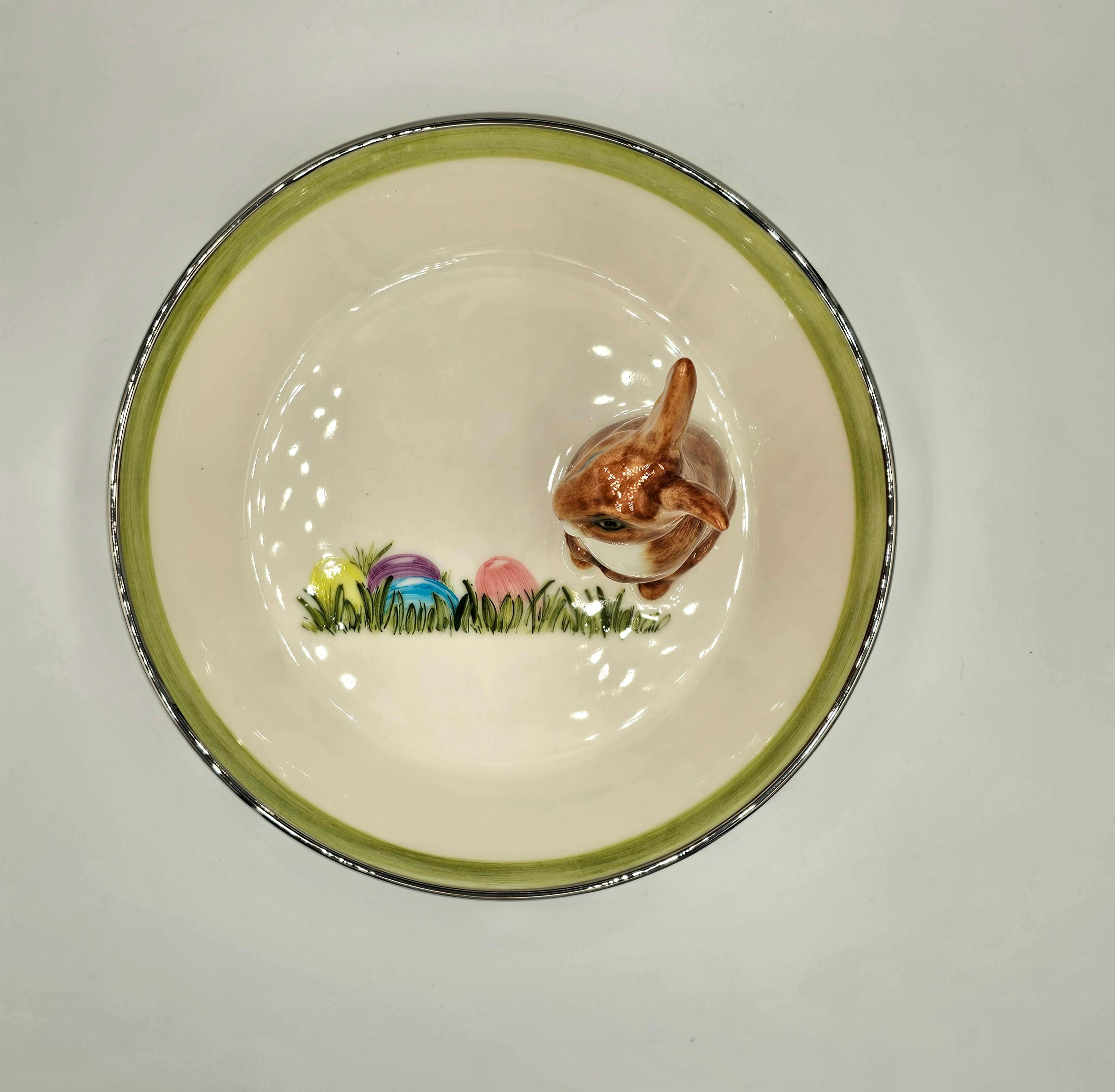 Bol en porcelaine entièrement fabriqué à la main avec une figure de lièvre de Pâques peinte de façon naturaliste avec des taches brunes. Le lapin est assis sur le côté du bol pour décorer les noix ou les bonbons autour.
Le plat à l'intérieur est