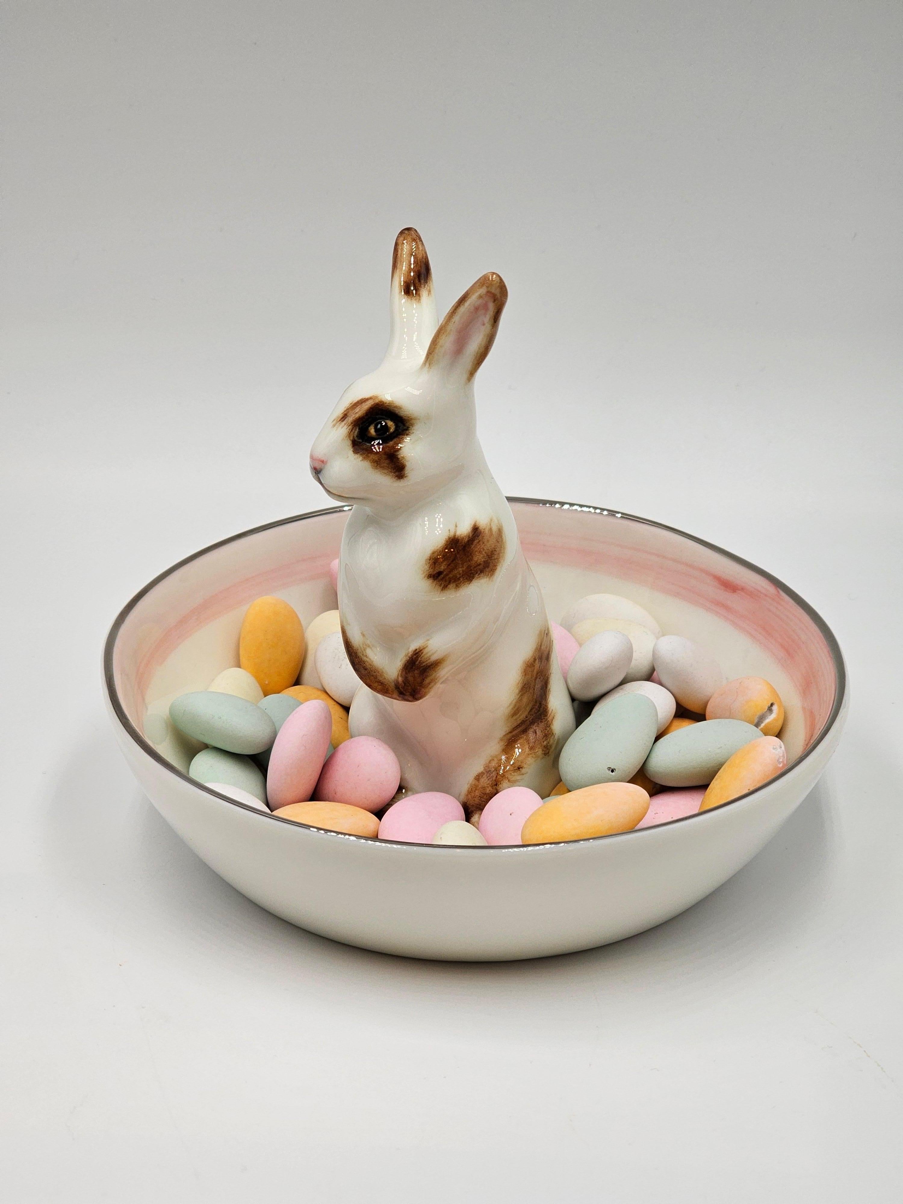 Completely handmade porcelain bowl with a hands-free naturalistic painted Easter hare figure with brown spots. The bunny is sitting in the middle of the bowl for decorating nuts or sweets around.
The dish inside is handsfree painted with colorful