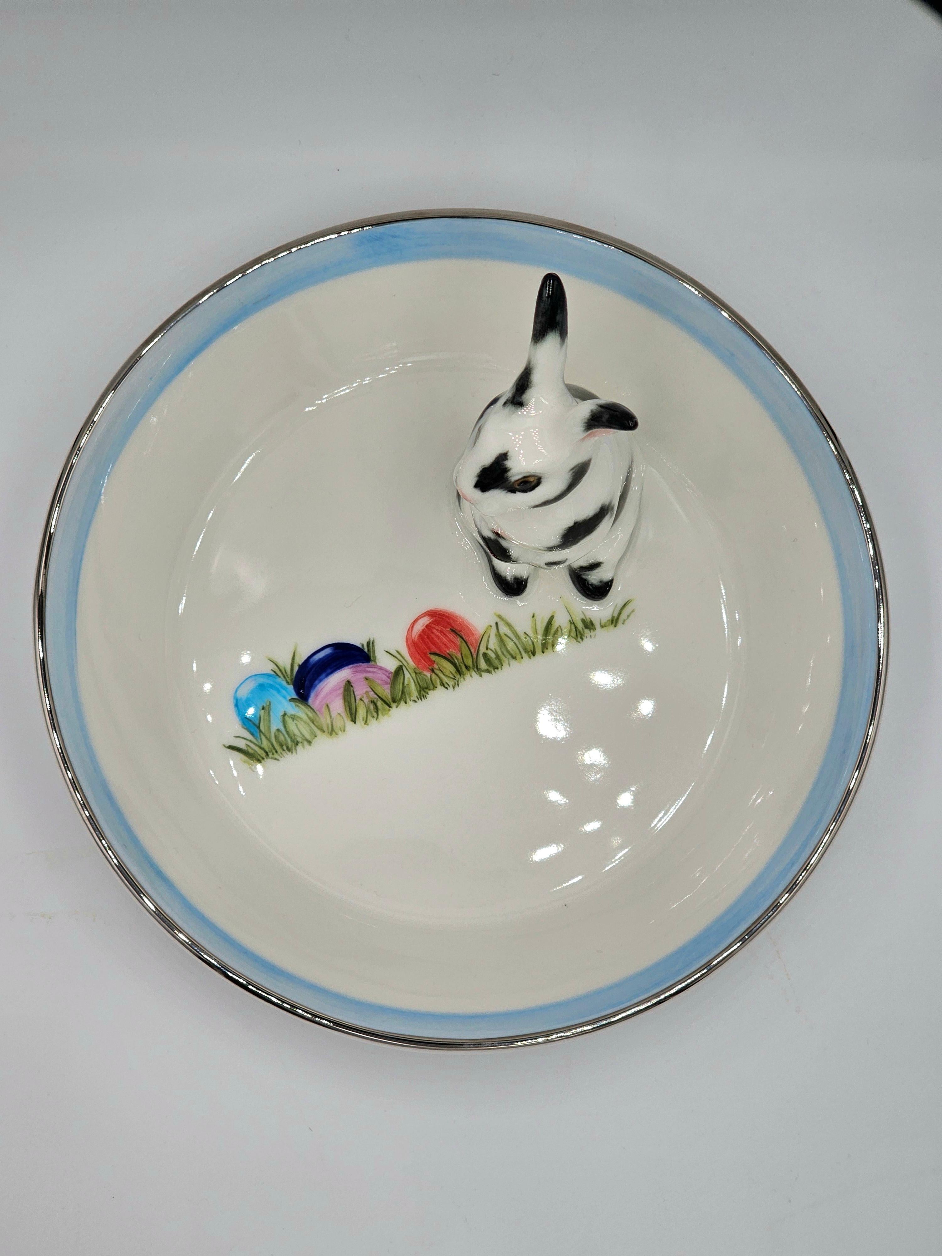 Completely handmade porcelain bowl with a hands-free naturalistic painted Easter hare figure with black spots. The bunny is sitting on the side of the bowl for decorating nuts or sweets around.
The dish inside is handsfree painted with colorful