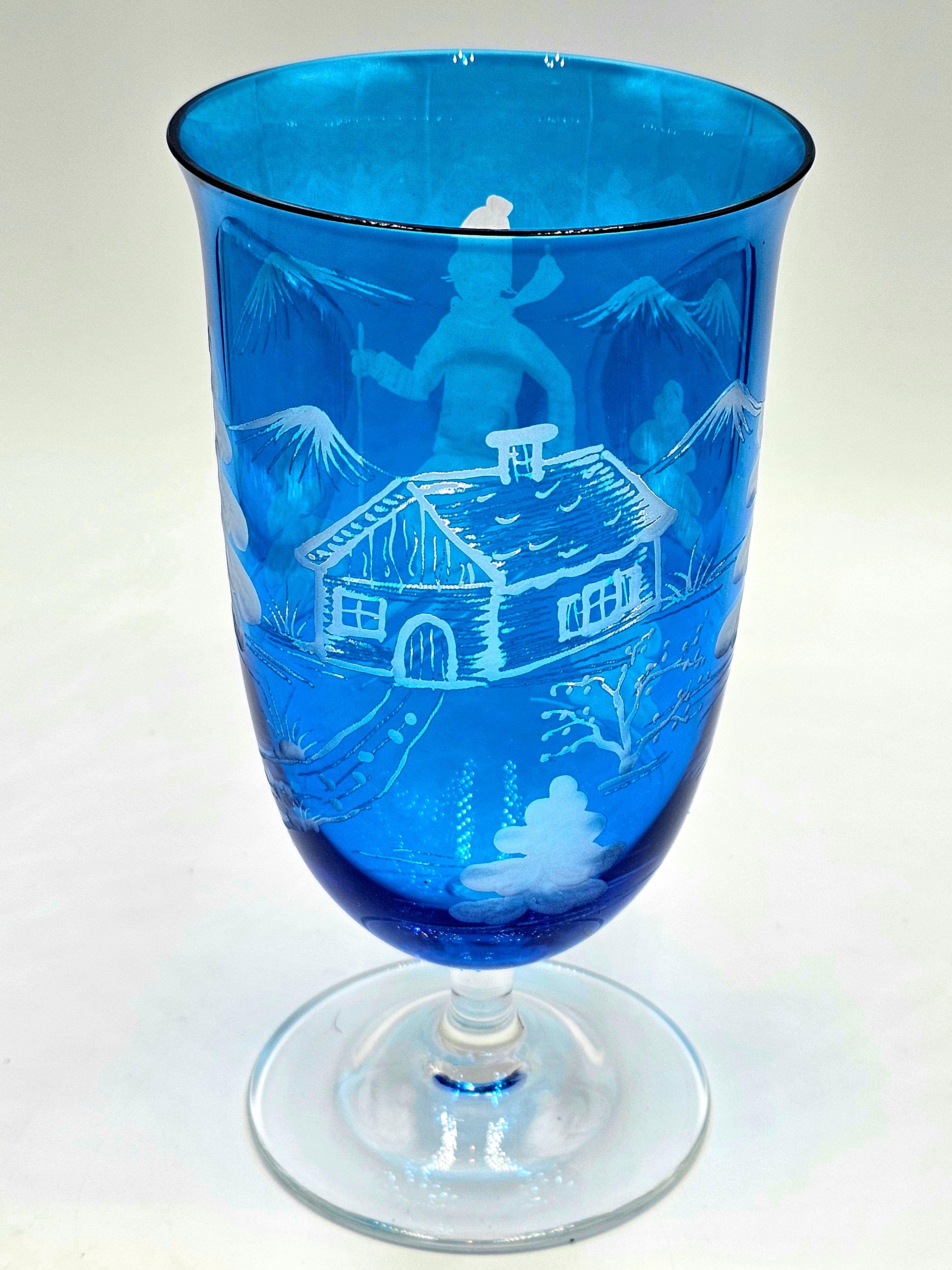 Set of six hand blown crystal glasses in blue with a hand-edged skier decor all around. The decor is a country style decor, showing a skier boy, trees and mountains and a chalet all-over the glass. A matching crystal carafe can be ordered in