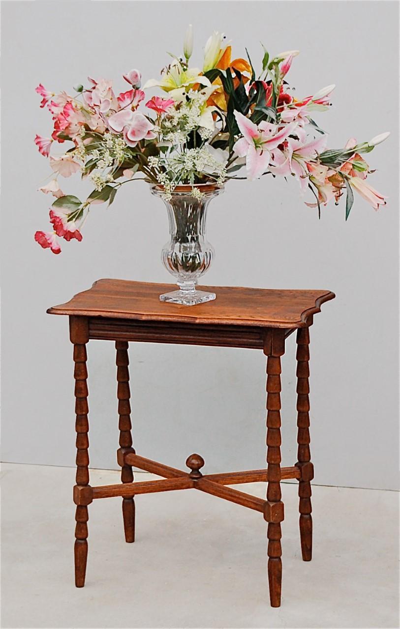 Mid size, country style, rectangular side table or occasional table on shapely carved legs joined by cross stretchers for added strength, with decorative, wooden finial at the centre. It has a rectangular top with scalloped or curved corners and