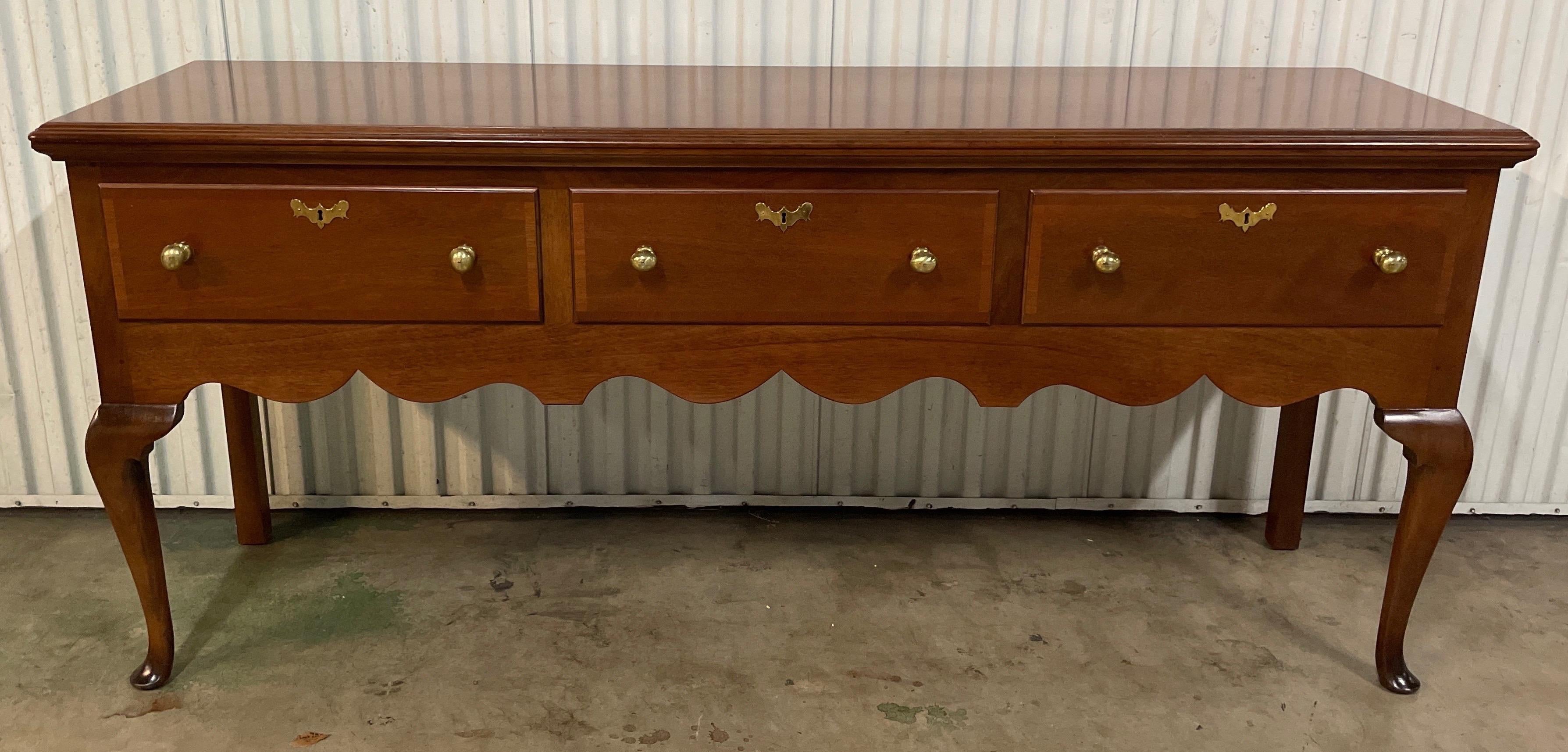 Hand crafted sideboard / buffet by Kittinger furniture company. This piece has three ample drawers with large brass pulls. The scalloped edge gives it a less formal look. This is a limited-edition piece made in conjunction with the Williamsburg