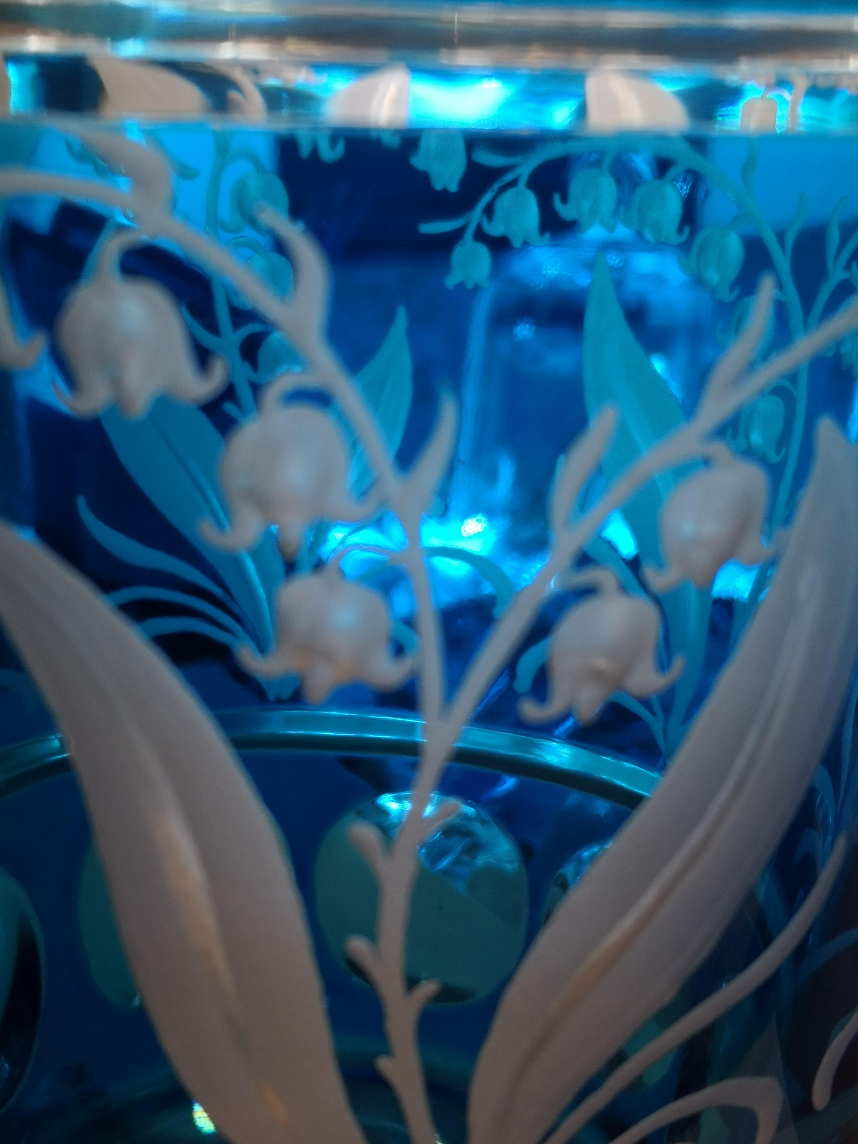 Vase aus mundgeblasenem blauem Kristallglas mit freihändig gravierter Maiglöckchengirlande rundherum. Die Glasvase ist komplett mundgeblasen und handgraviert im Landhausstil von Glaskünstlern in Bayern für die Sofina Boutique Kitzbühel. Das hier