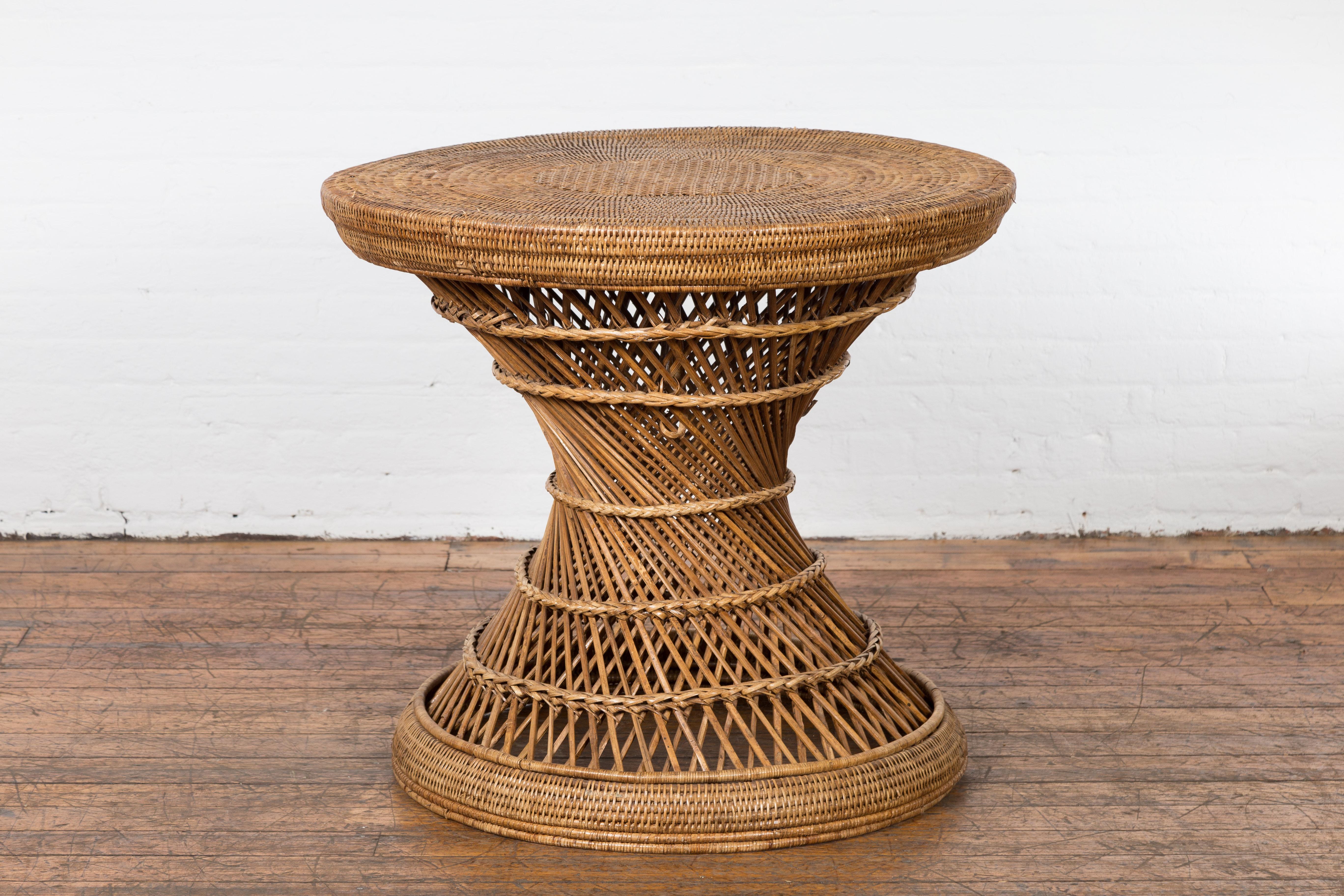 A rustic country style Thai drum table from the mid 20th century made of woven rattan with circular top, hourglass shape and twisted center. Evoking the warmth and charm of mid 20th-century Thai craftsmanship, this rustic country style drum table is