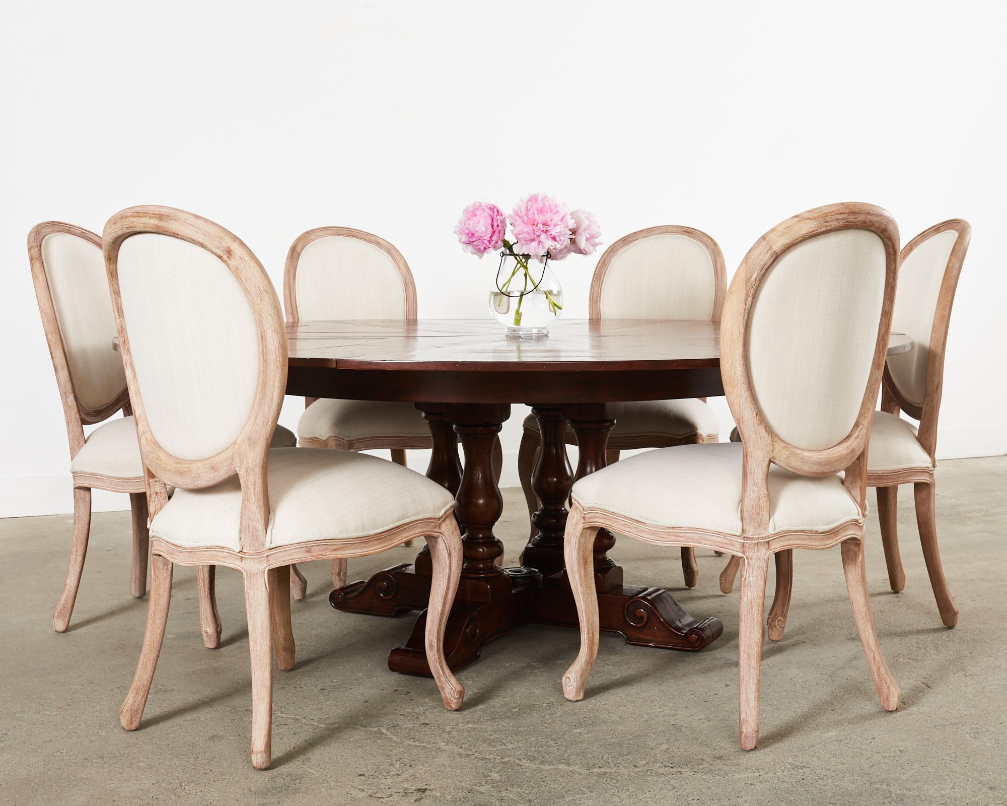 Grand mahogany dining table featuring an ingenious extending parquetry round top with hidden leaves that extends from a 60 inch diameter table to an 85 inch diameter table. The Sylvan dining table hand-crafted by artisans for Theodore Alexander from