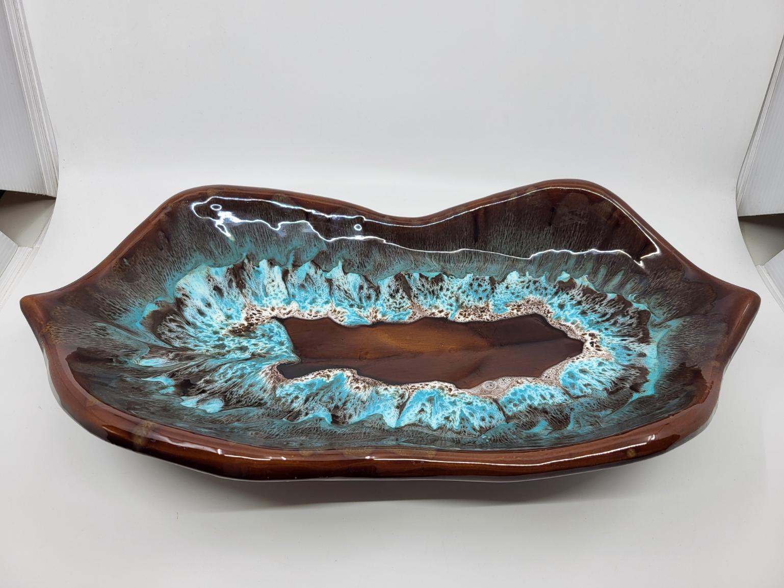 Cette coupe Vallauris en céramique émaillée, datant des années 1960/70 et provenant de la Côte d'Azur, se distingue par sa grande taille et ses couleurs marron et bleue. Mesurant 45 cm de long, 24 cm de large et 9 cm de profondeur, elle constitue