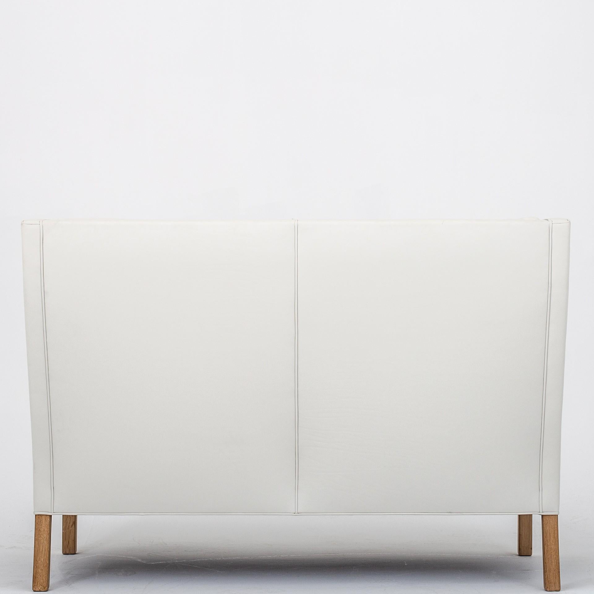 BM 2192 - Coupésofa 2-seat sofa i original white leather with legs in oak. Maker Fredericia Furniture.