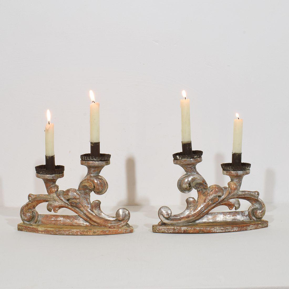 Coppia di piccoli portacandele in legno intagliato con tracce di doratura in foglia d'argento.
Italia, 1750 circa
Intemperie e piccole perdite e vecchie riparazioni.

Le misure sono individuali.
H. H. 20cm  L:27cm D:8cm 