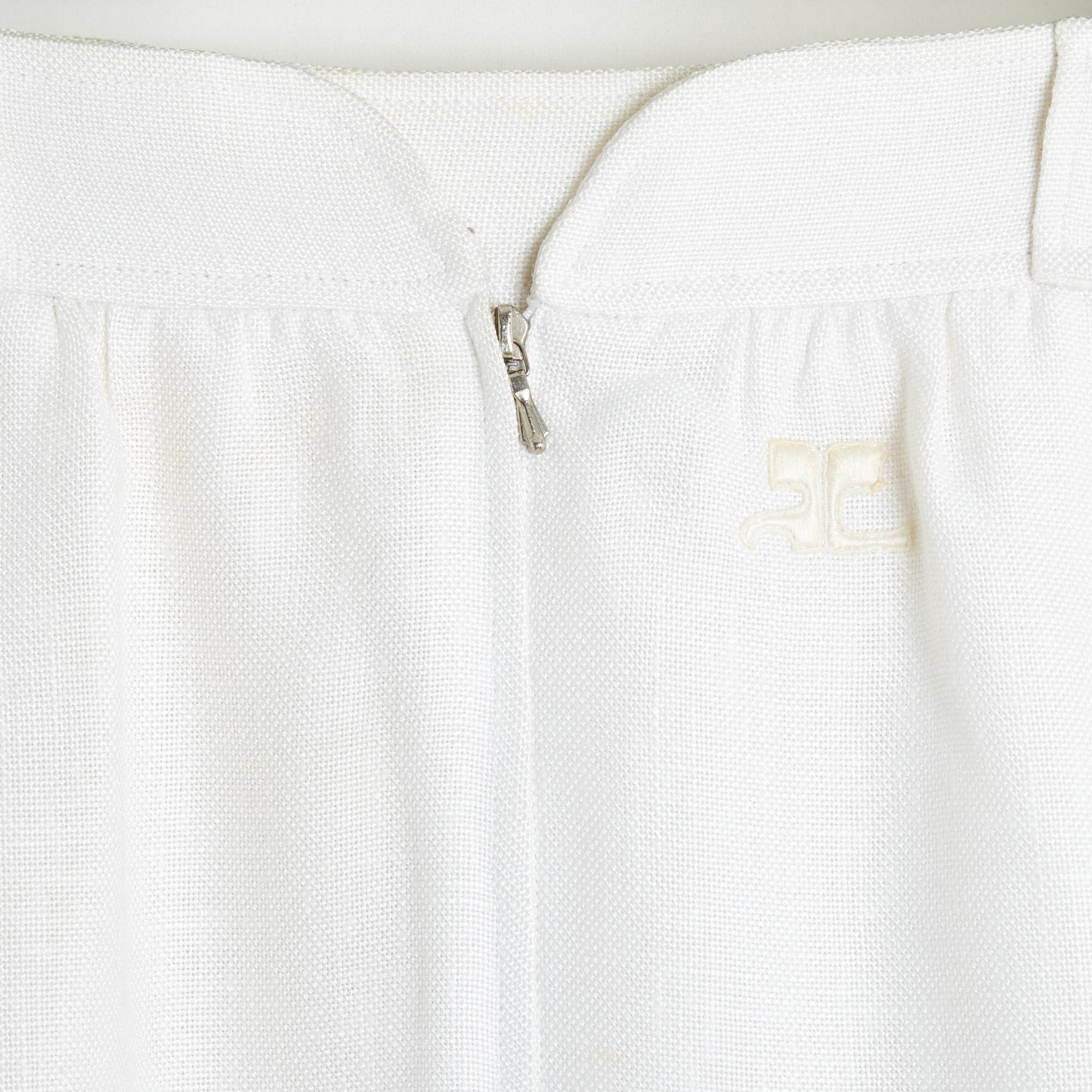 Courrèges skirt circa 1980 in white (or off-white) rayon braid, mid-length and straight; very slightly flared, 2 large cargo pockets in front, belt with belt loops, closed in front by a zip and a hook with rounded cutout, embroidered logo, lining in