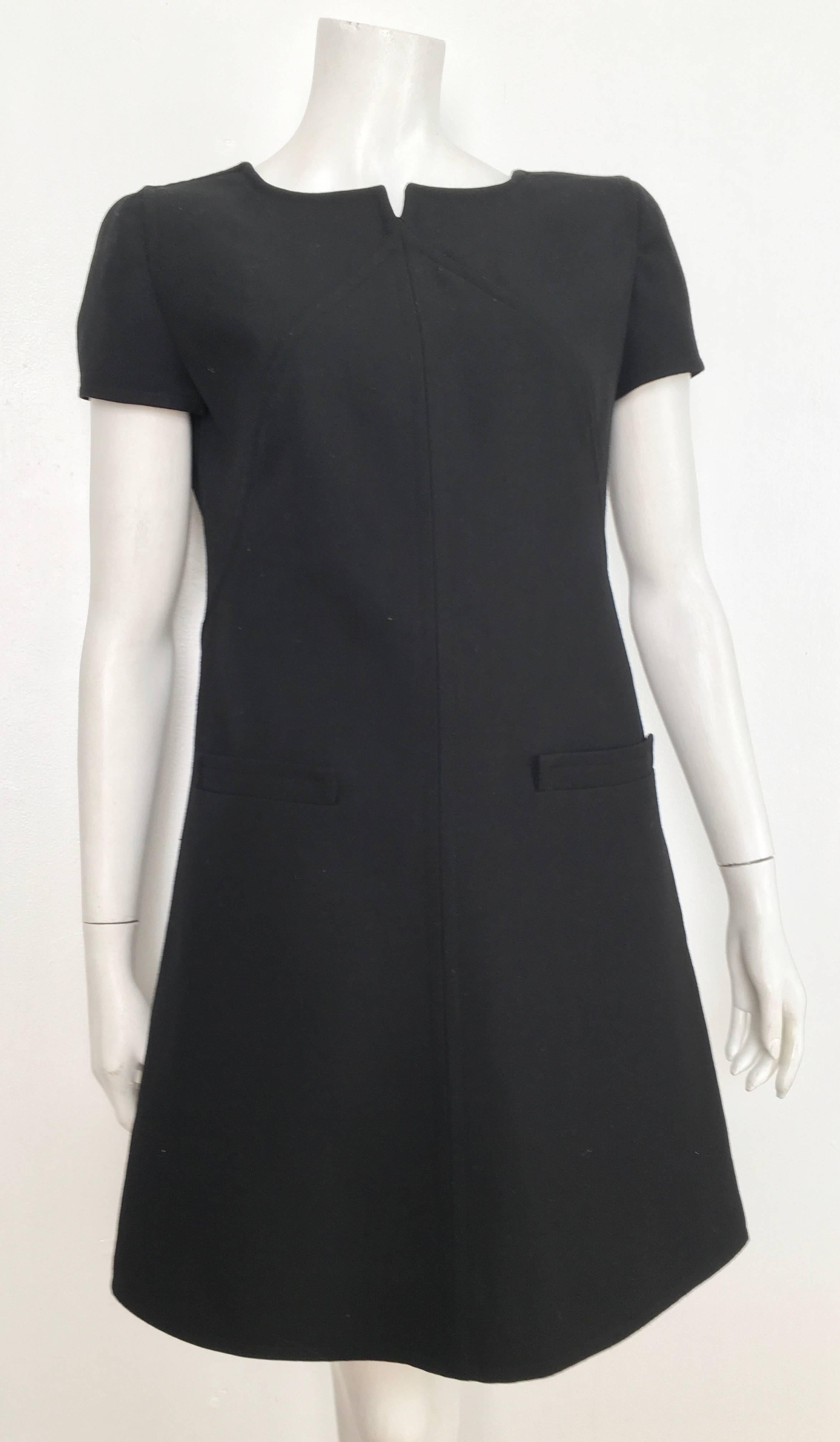 Courreges black wool short sleeve dress with front pockets is a French size 40 and fits a size 8 and has never been worn.  Ladies please grab your tape measure so you can measure your bust, waist & hips to make certain this gorgeous LBD will fit