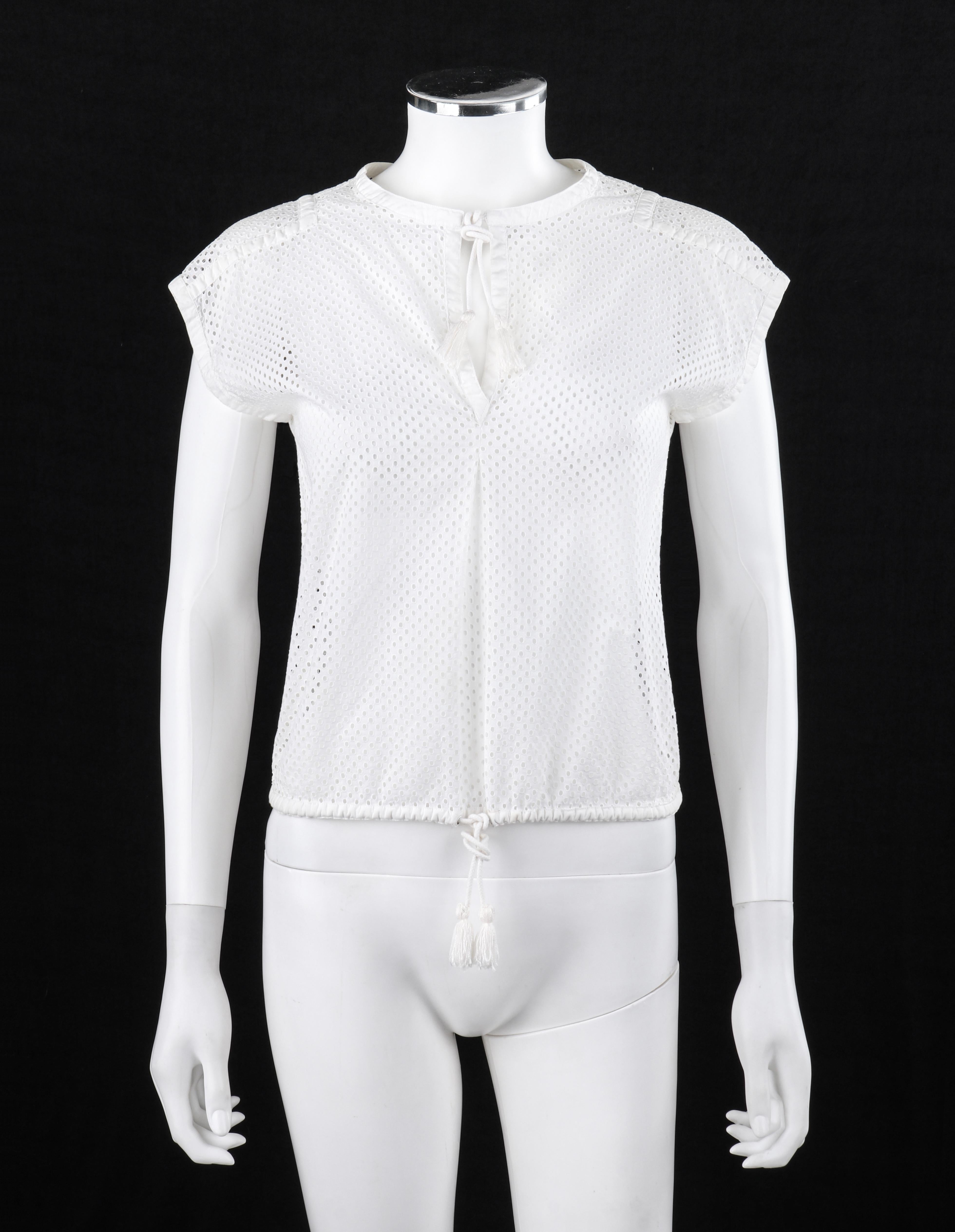 COURREGES c.1980’s Extended Shoulder White Circle Eyelet Embroidered Tassel Drawstring Top 
 
Brand / Manufacturer: Courreges 
Circas: 1980’s
Style: Sleeveless shirt / extended shoulder
Color(s): White
Lined: No
Marked Fabric Content: 100%