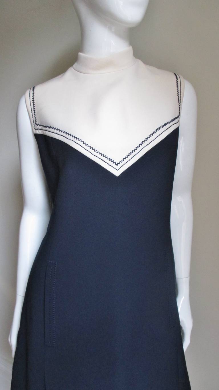 A fabulous navy and off white color block silk blend dress from Courreges.  It is sleeveless, semi fitted with a small stand up collar.  It has an off white yoke pointed in the front and a straight across in the back highlighted with rows of