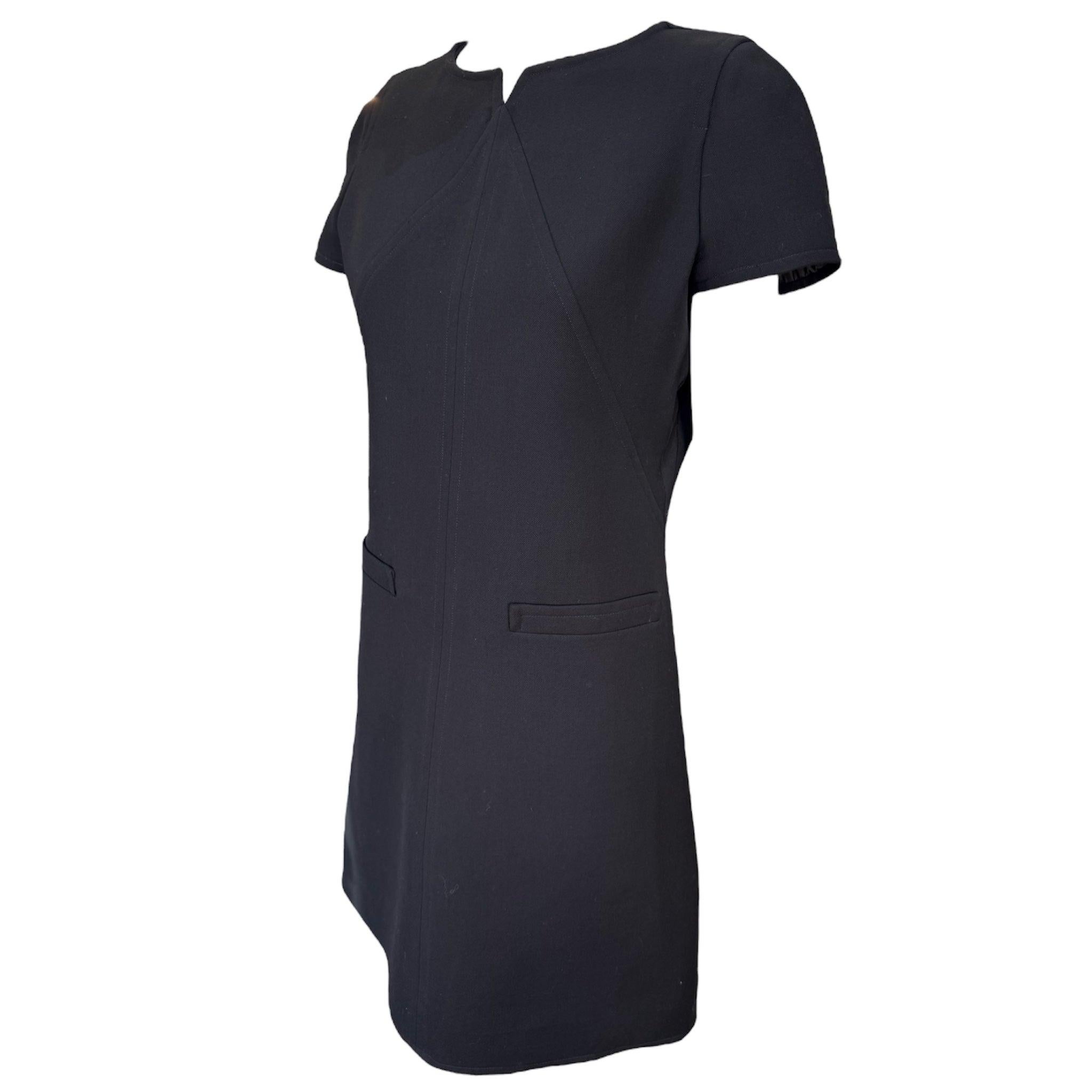 Eternally chic mod mini dress by Courreges. Circa 1990's. Classically straight A-Line silhouette enhanced by the tailoring and top-stitching. Notched collar and short capped sleeves. Back belt button detail. Two faux pockets at front hips. Wool