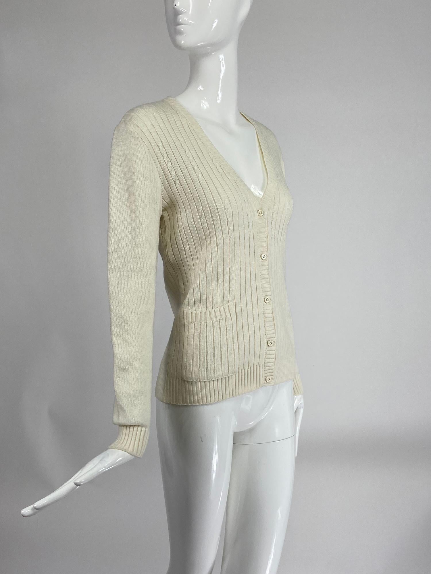 Courreges off white ribbed and cable knit cardigan sweater. Long sleeve, V neck sweater, the body of the sweater is done in rib knit with interspersed rows of cable knit. The sleeves are plain knit with ribbed cuffs. Ribbed facings, the sweater