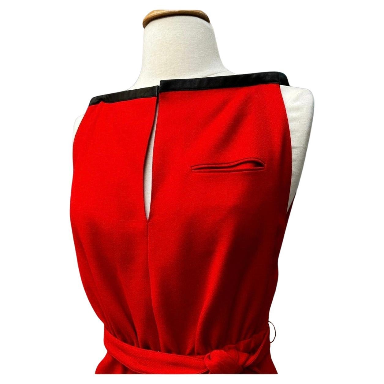 Vintage André Courrèges sleeveless red wool dress with black leather trim. A-line silhouette. Straight neckline. Keyhole opening at bodice with hook and eye closure at neck. Single welt pocket on the bodice. Two hip pockets. Side slit hem. Elastic