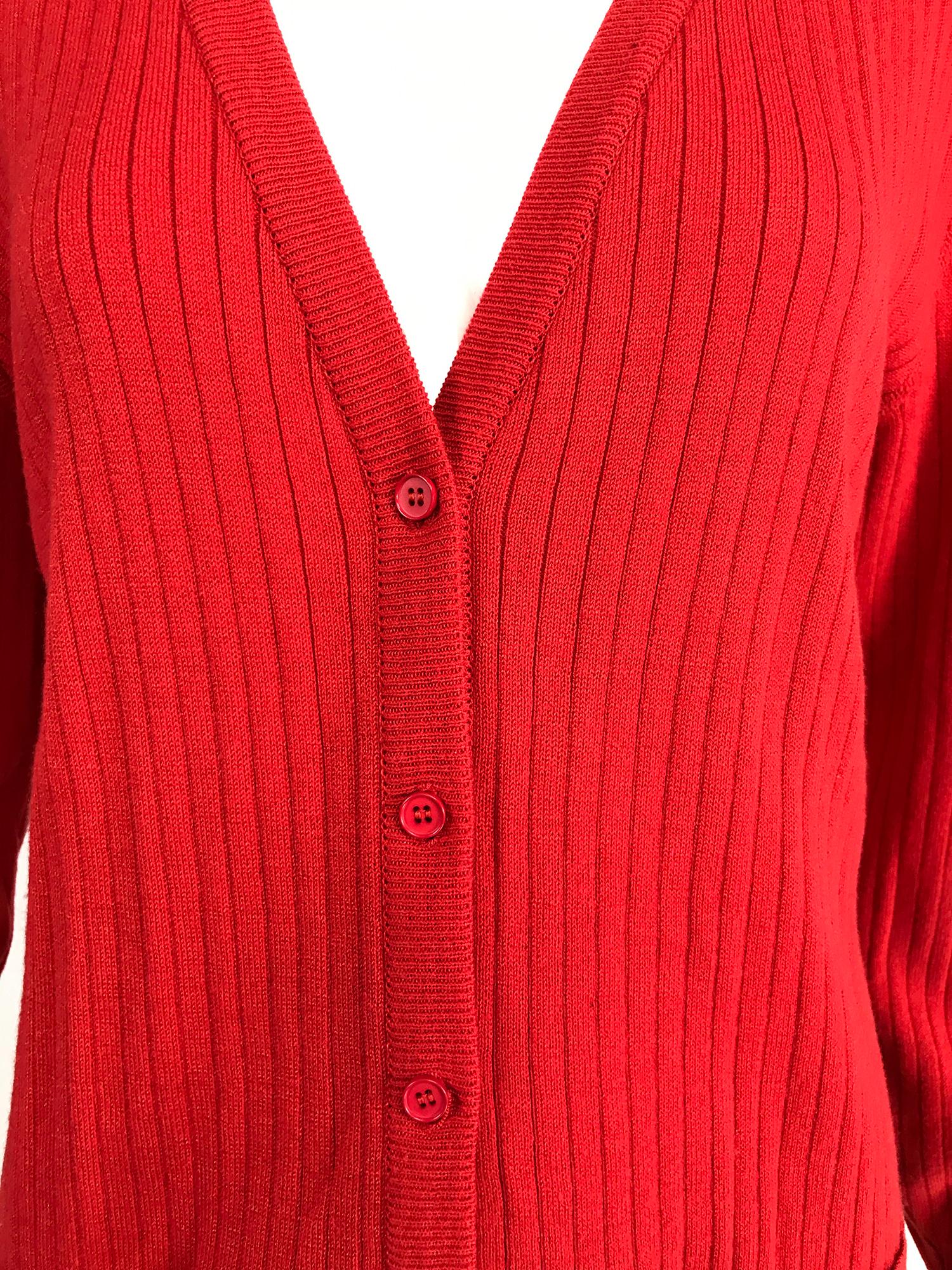 Courreges red V neck ribbed cardigan sweater 1980s. Long sleeve sweater with narrow ribs, hip front pockets, closes at the front with 6 red buttons. Fits like a size small-medium. 
In excellent wearable condition.  All our clothing is dry cleaned