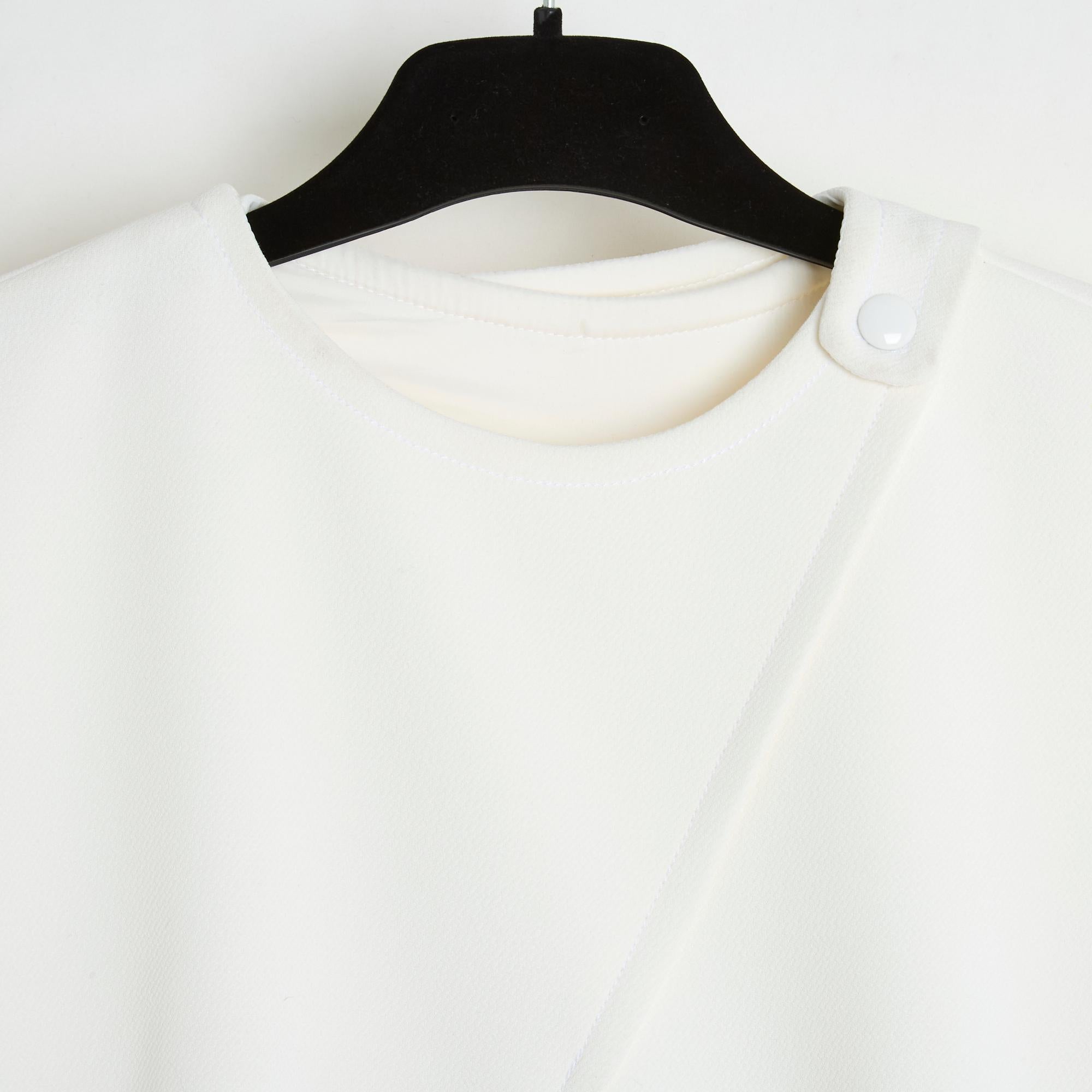 Courrèges A Line model dress with cutouts at the front and back in thick, almost white ecru wool knit, round neck with snap opening on the side, 2 slanted slit pockets, short sleeves, zip and hook closure at the back. Size 42FR, i.e. UK 14 and US12: