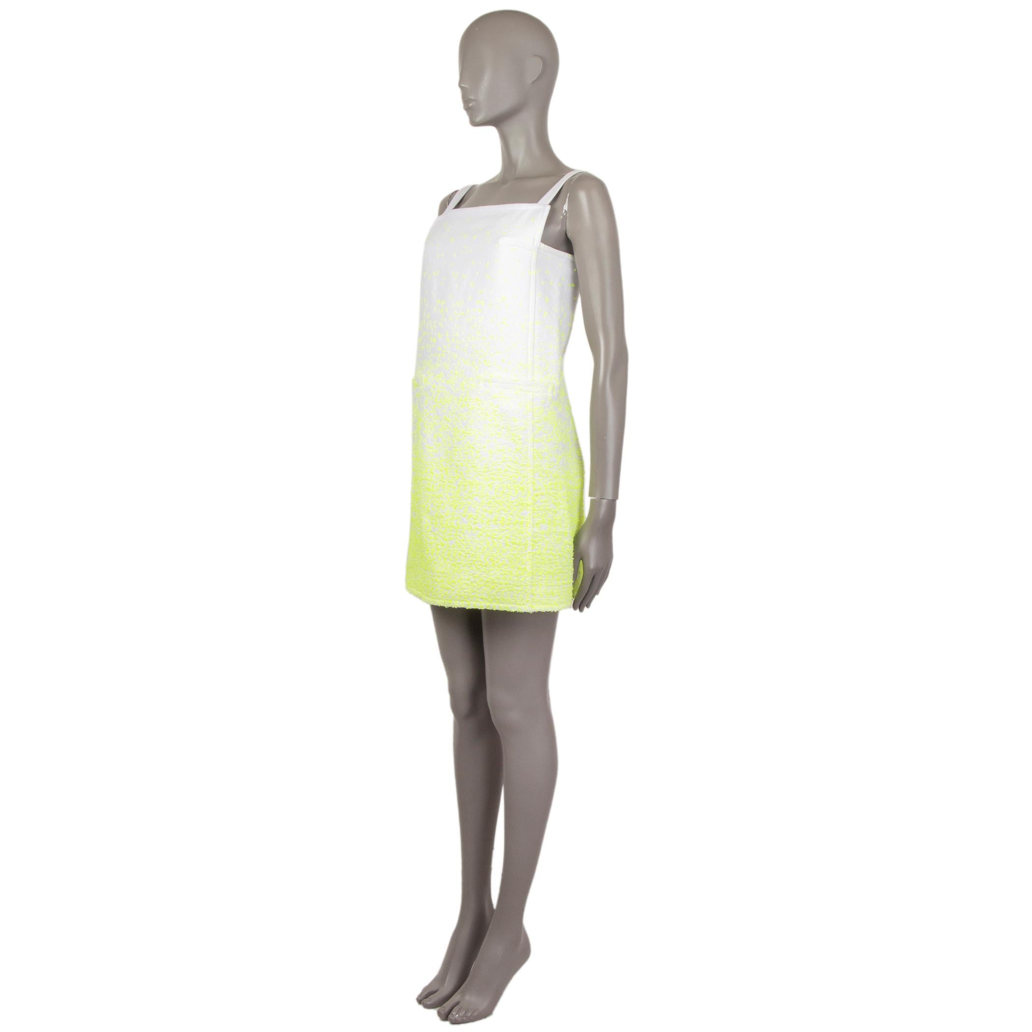 100% authentic Courreges textured pinafore dress in white and neon yellow cotton (32%), paper (32%), acrylic (28%), and nylon (8%). With two pockets on the front. Closes with invisible zipper on the side. Lined in white fabric. Has been worn and is