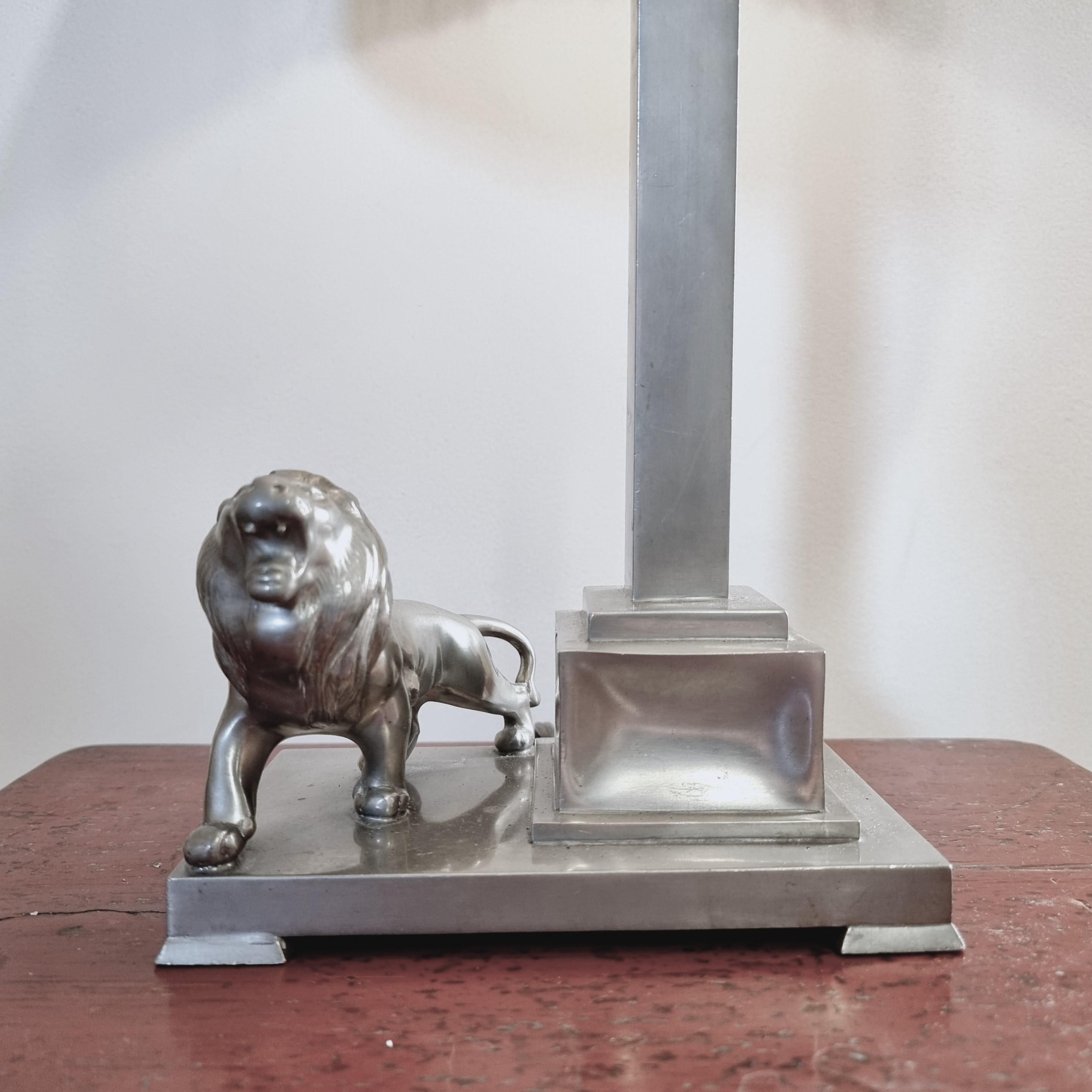 Lampe de table en étain avec décor de lion, par le joaillier de la cour Ernst Svedbom. Daté de 1932 (F8), grâce suédoise/art déco.

Avec les poinçons des fabricants. En bon état, douille avec bosses non visibles lorsque l'abat-jour est allumé.