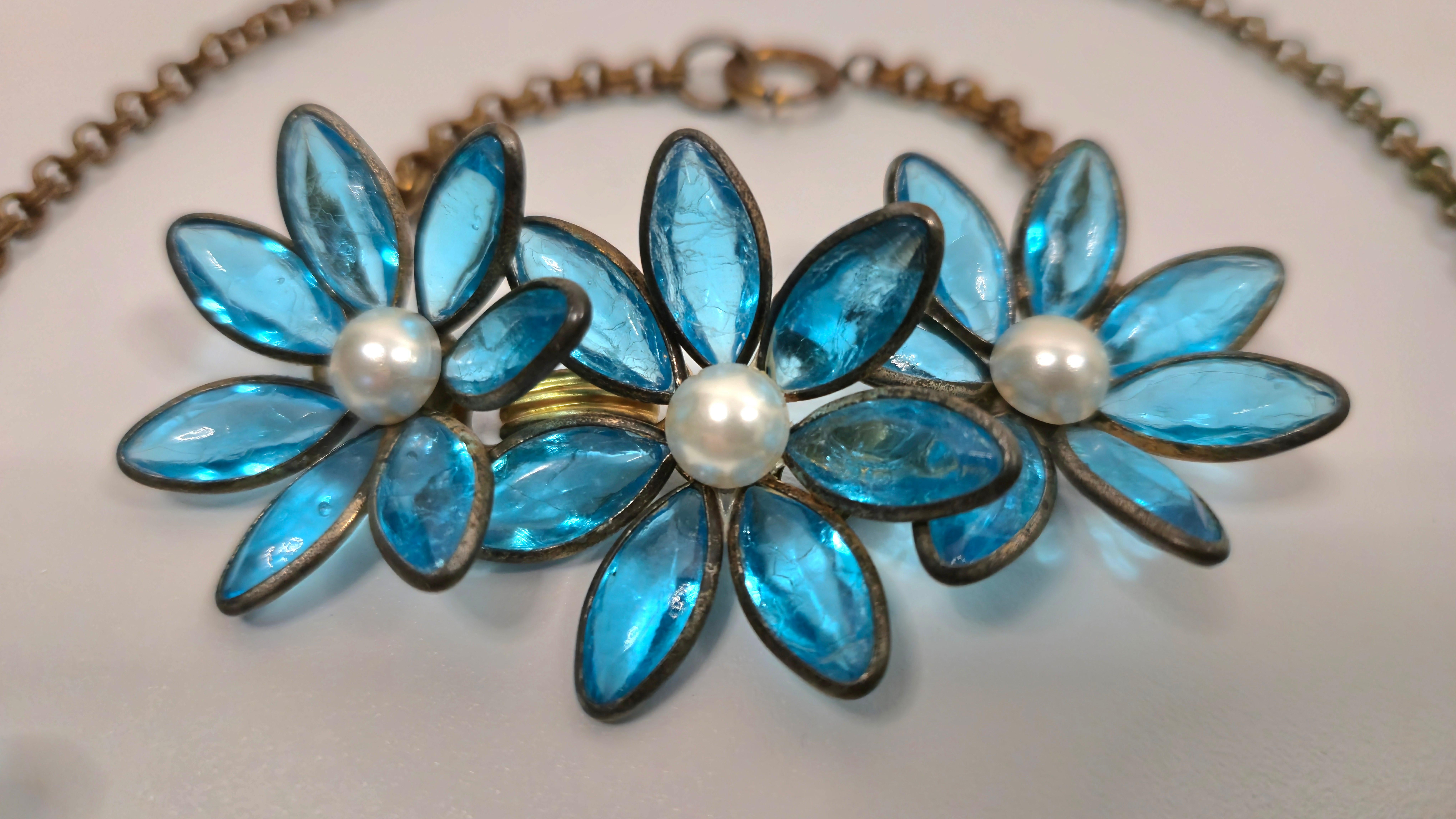 Esta pieza de alta costura de la Maison Gripoix francesa de principios del siglo XX, realizada por encargo de Coco Chanel, presenta ocho colgantes florales cuyos marcos de pétalos de metal con forma de margaritas suspenden un vidrio transparente