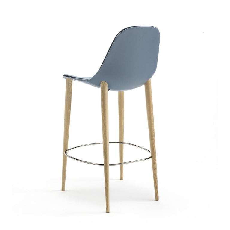 This chair's Minimalist design makes it perfect for any environment. Its structure features four, fixed legs in natural ashwood and a bright chrome footrest. Its aluminum shell is covered in North-Pole-colored soft leather. The chair can be