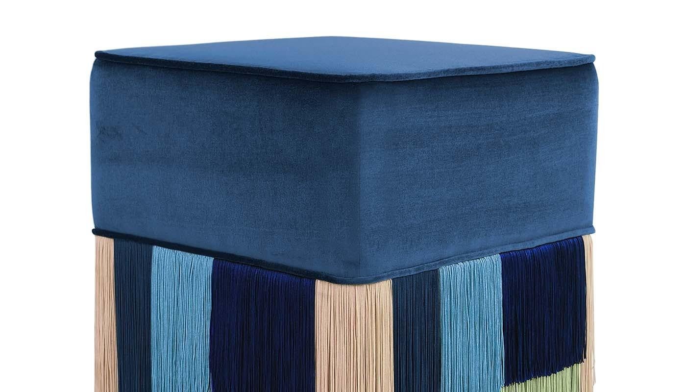 Ce pouf Art déco couture, qui respire le calme et la sérénité, se distingue par ses franges aux couleurs douces qui contrastent brillamment avec un coussin en velours bleu cobalt uni. Les franges, dans des tons variés de bleu royal et bleu marine,