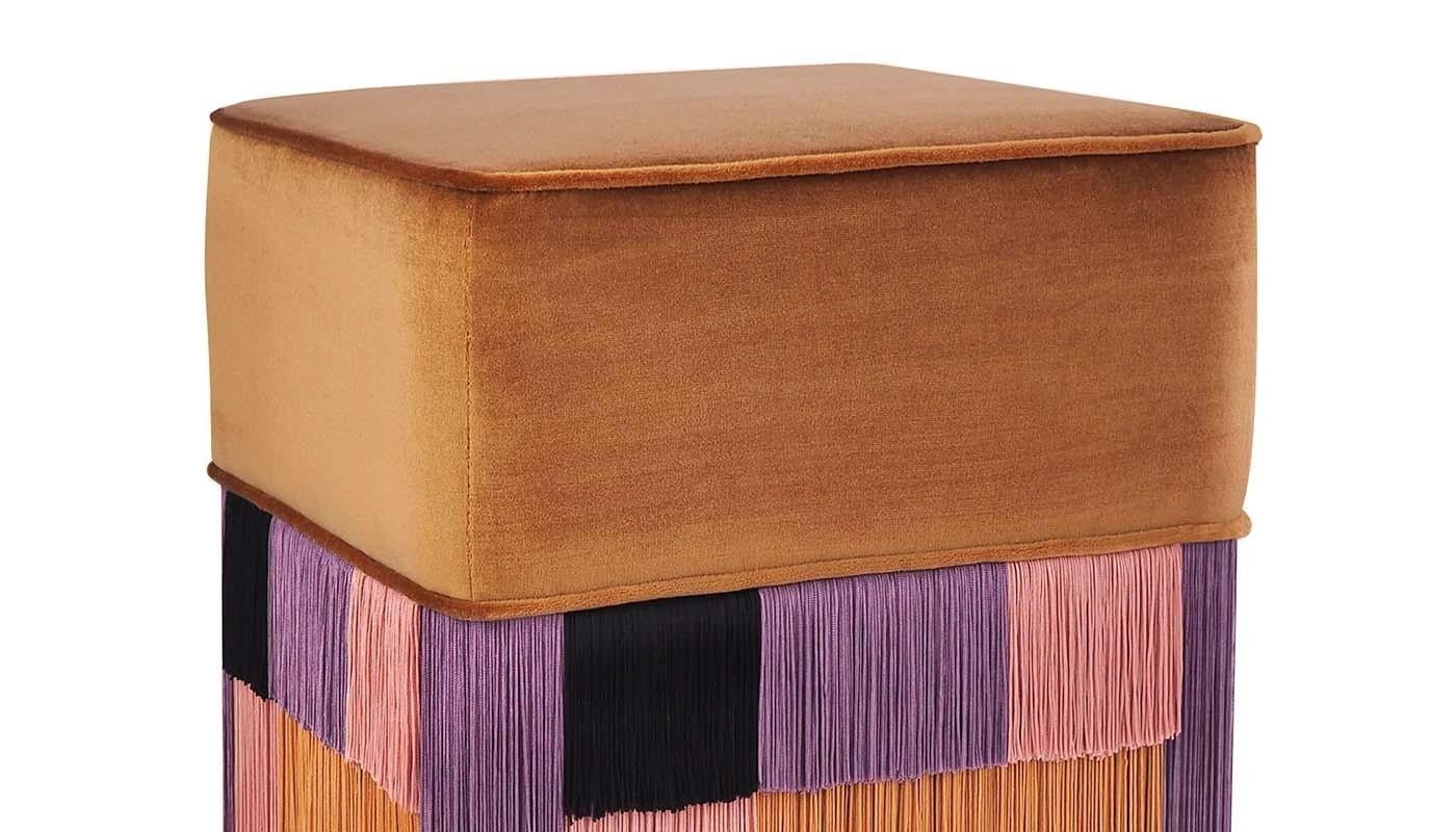 This lively velvet pouf perfectly expresses the energy and glamour of the Art Deco style. With its solid beige, refined cushion from which black, lilac, peach-pink, and melon-colored layers hang in geometric shapes, this ottoman embodies the concept