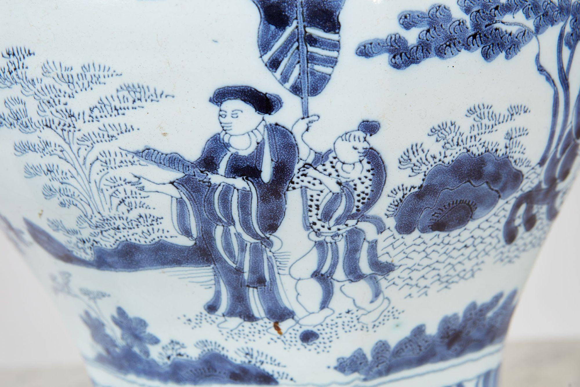 An 18th century blue and white covered delft jar having elaborate hand-painted oriental scenes of a master in his garden being fanned by a courtier, the master being accompanied by a hunter on horseback and two courtiers, and on the lid figures