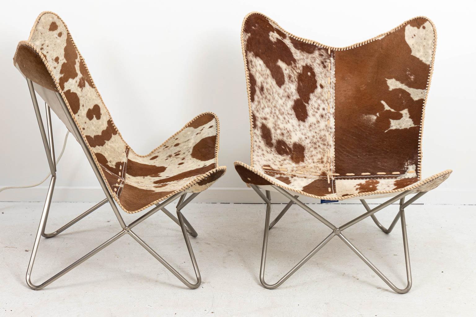 Cow hide upholstered butterfly chairs with metal legs. Please note of wear consistent with age.