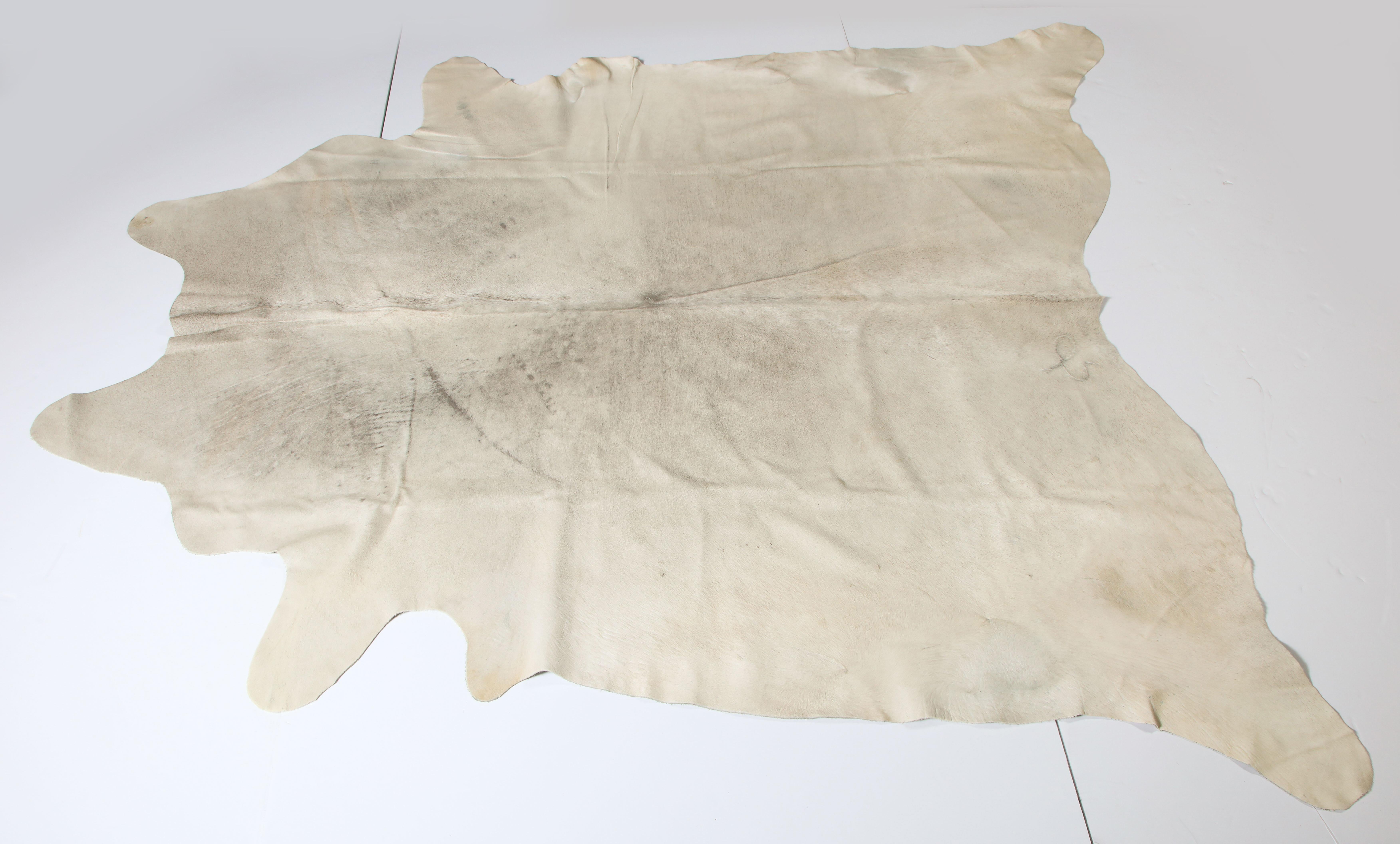 Cow hide, lightly vintage.
If you measure from leg to leg, one side is 111 inches and in the other direction it is 105 inches.
Cream color with a little bit of grey.
Good condition.