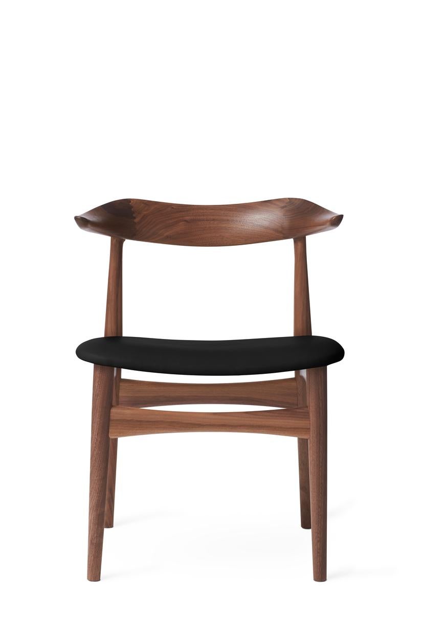 Cow Horn chair walnut black leather by Warm Nordic
Dimensions: D 55 x W 48 x H 74 cm
Material: Oiled solid walnut frame, Textile or leather upholstery.
Weight: 7.5 kg
Also available in different colours and finishes.

The Cow Horn Chair is an