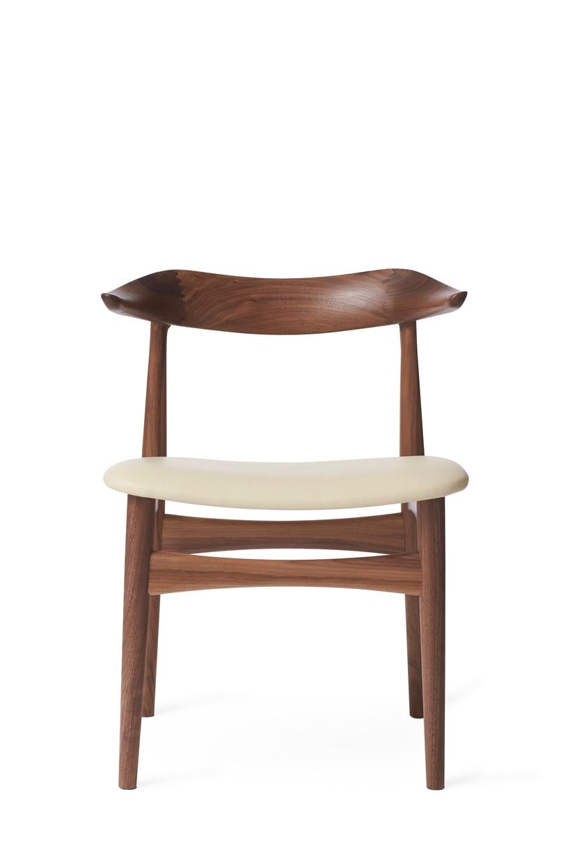 Cow horn chair walnut ivory leather by Warm Nordic
Dimensions: D55 x W48 x H 74 cm
Material: oiled solid walnut frame, textile or leather upholstery.
Weight: 7.5 kg
Also available in different colours and finishes. 

The Cow Horn Chair is an