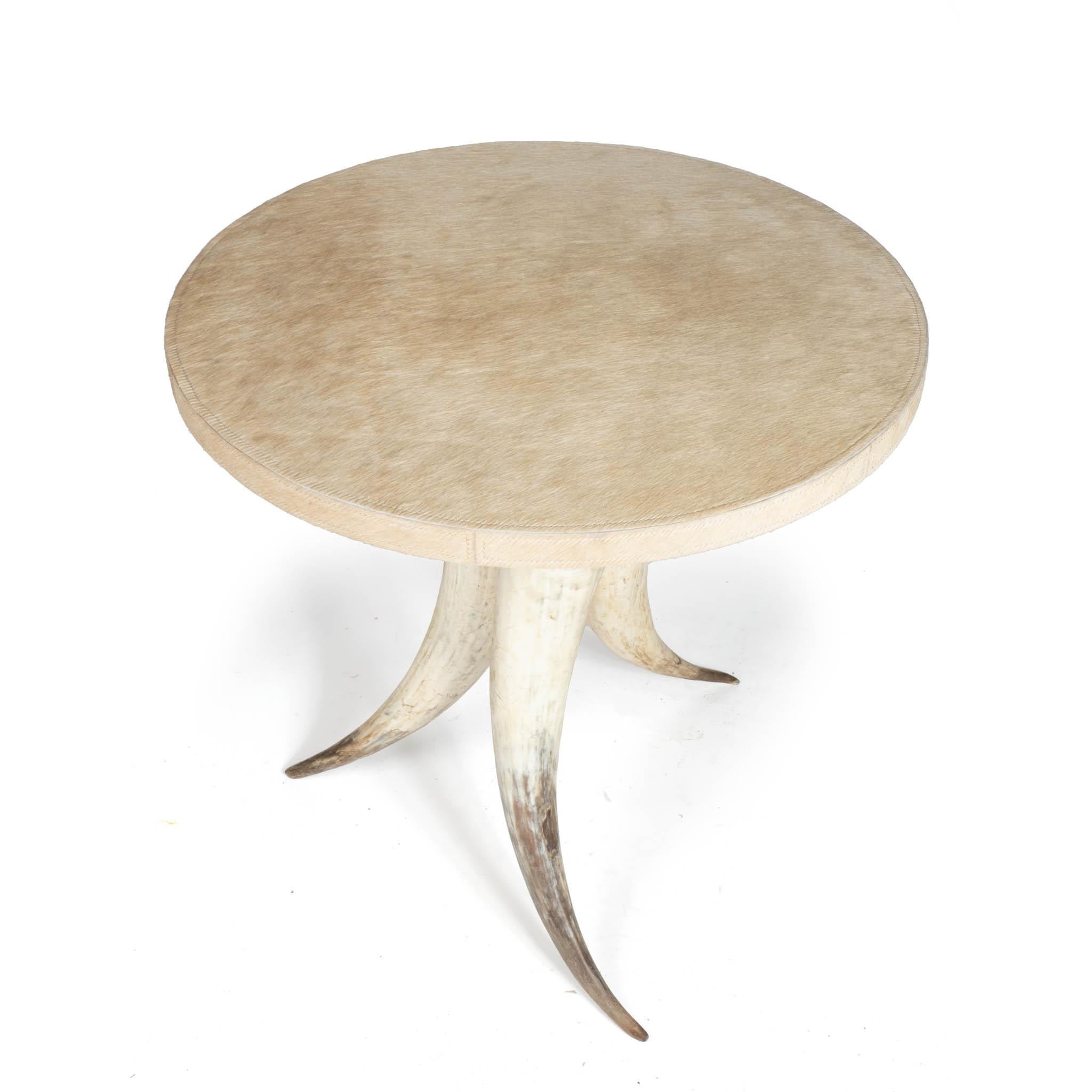 Complément naturellement luxueux de toute pièce, cette table d'appoint repose sur un trio de cornes de vache issues de l'agriculture durable et est surmontée d'une surface ronde surdimensionnée enveloppée de cuir à poils surpiqués. En raison de