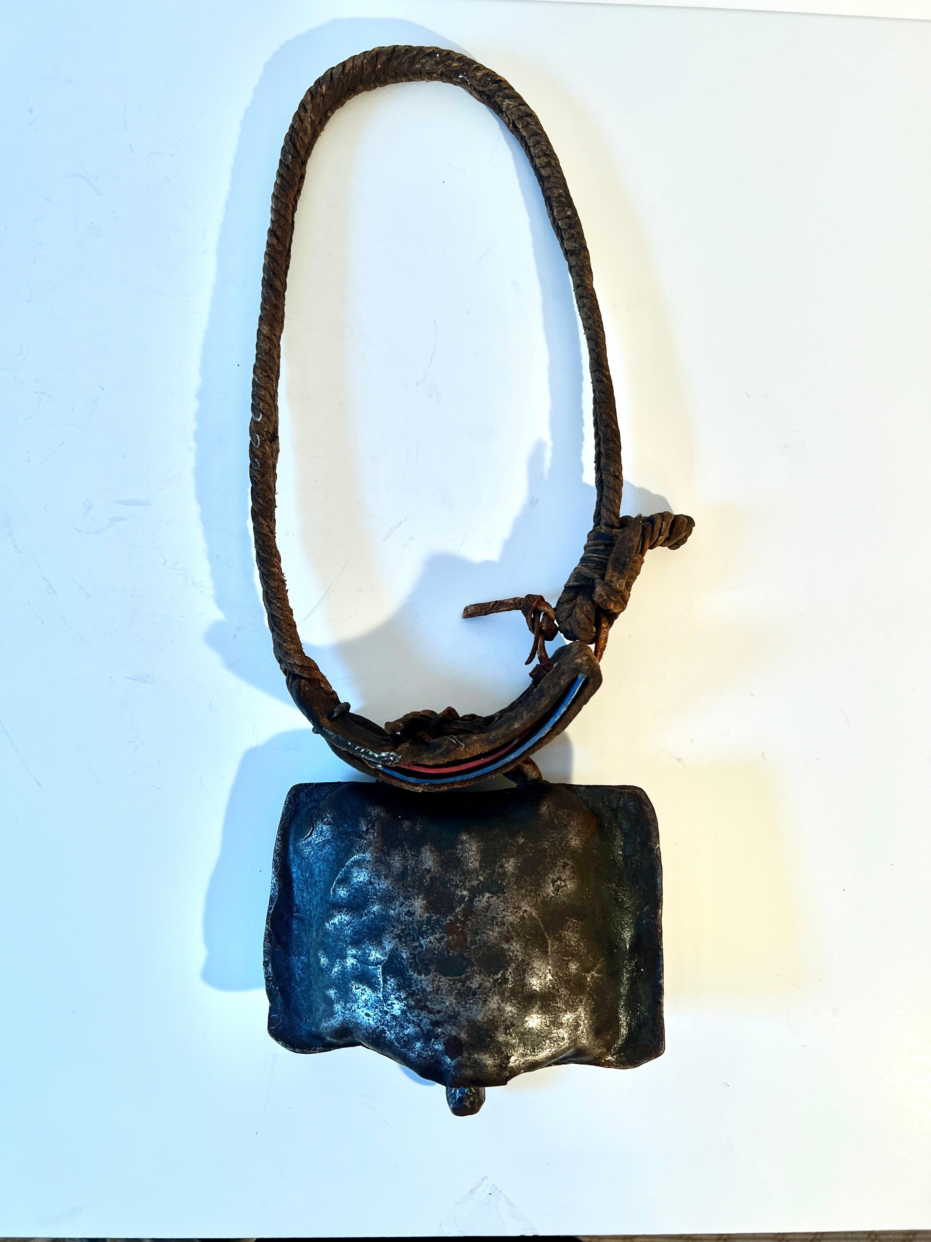 A vintage cowbell made of Steel, metal, and braided leather or the collar.

This is a great decorative piece, however the bell works great.  A great place to put this is over a door knob, allowing one to know when the door opens or moves...  Also a
