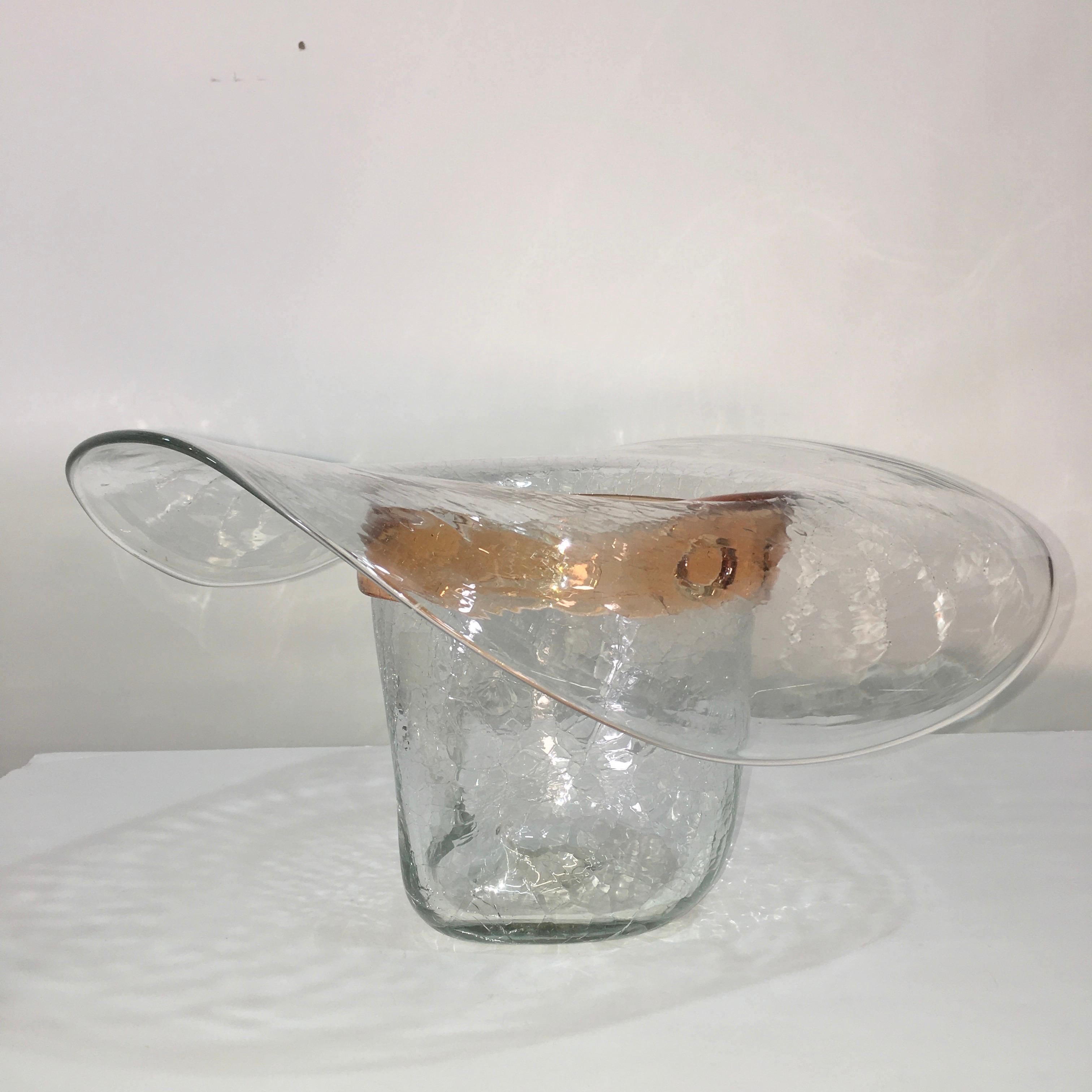 Blenko Glass ice bucket in the form of a cowboy hat by Don Shepherd. The main photo makes this ice bucket/bottle chiller appear golden orange when in fact only the hat band is golden orange while the rest of the hat is clear. Residual label present.