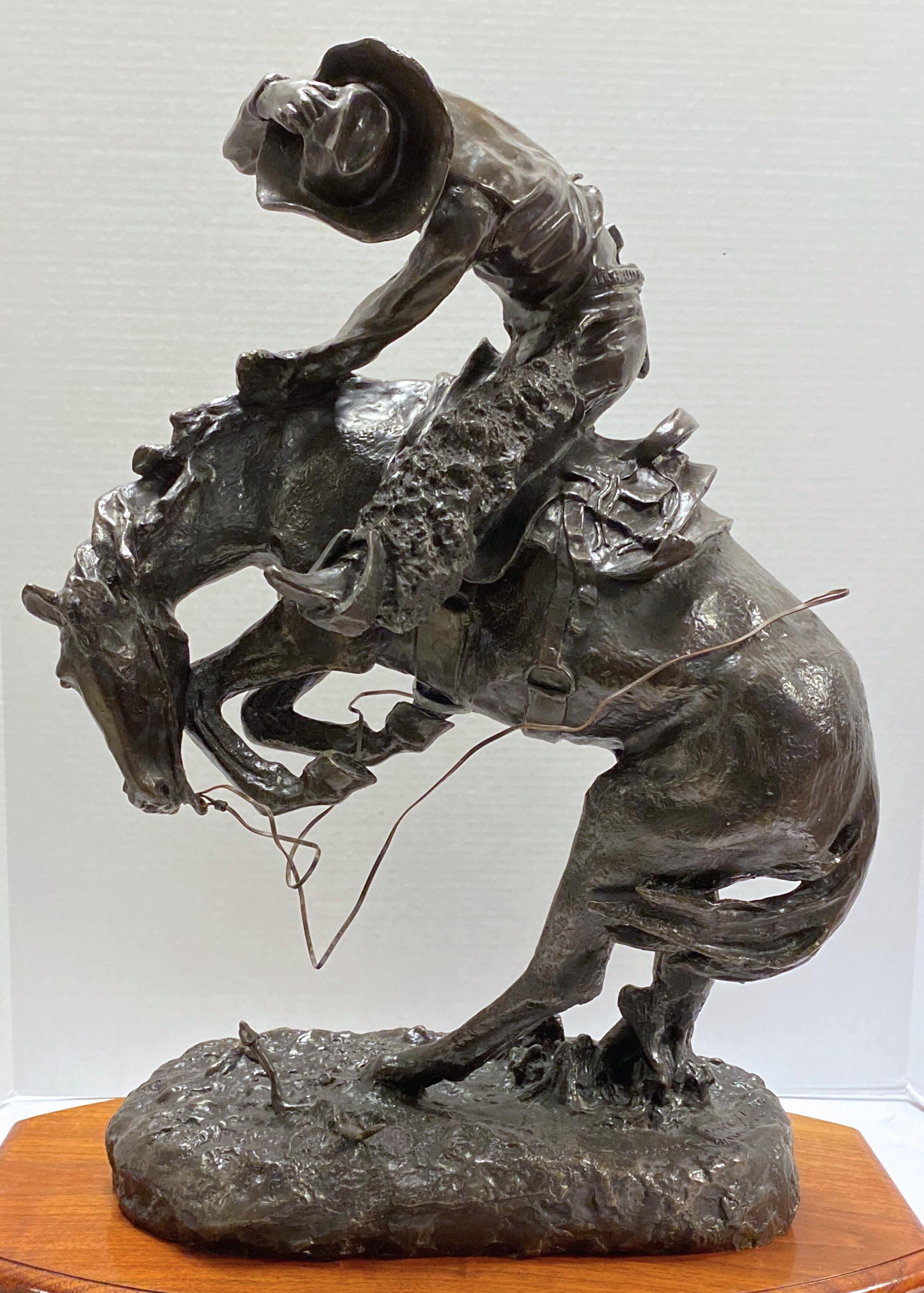 Cowboy on Bronco Bronze After Remington, very finely cast and mounted on carved wooden plinth with stained finish.
